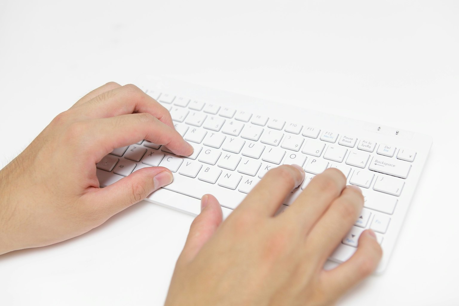Mani che digitano su una tastiera bianca