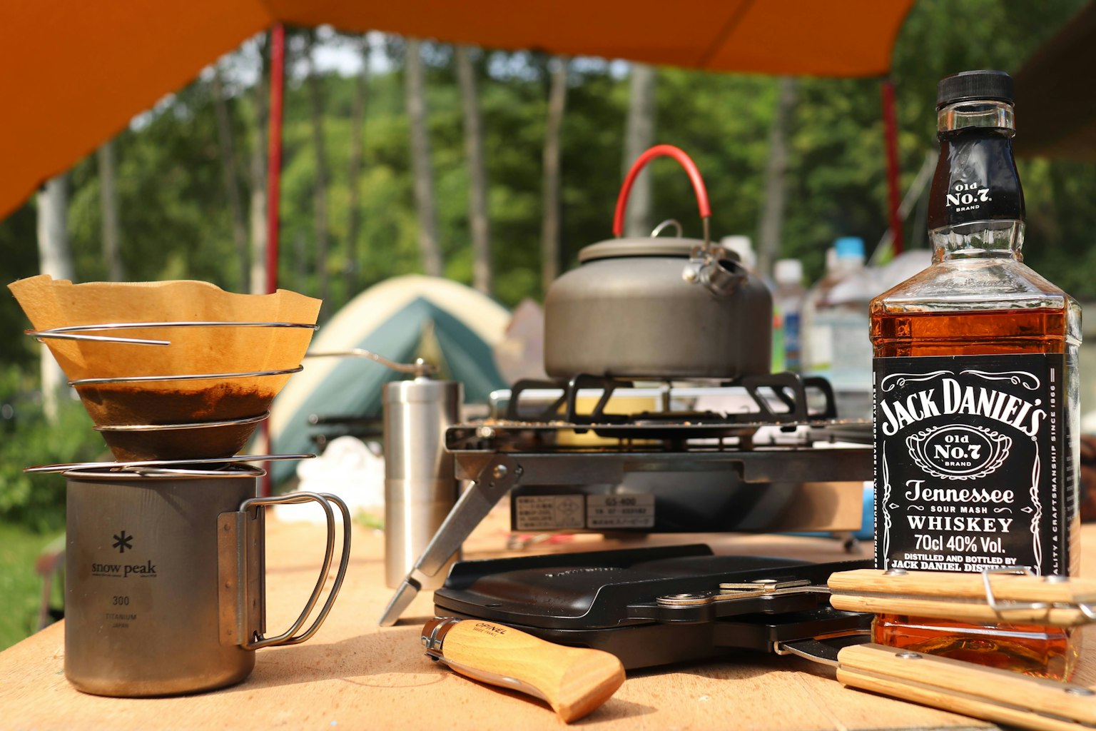 Camping-Szene mit Kaffeebereitungsgeräten und Jack Daniel's Whiskey