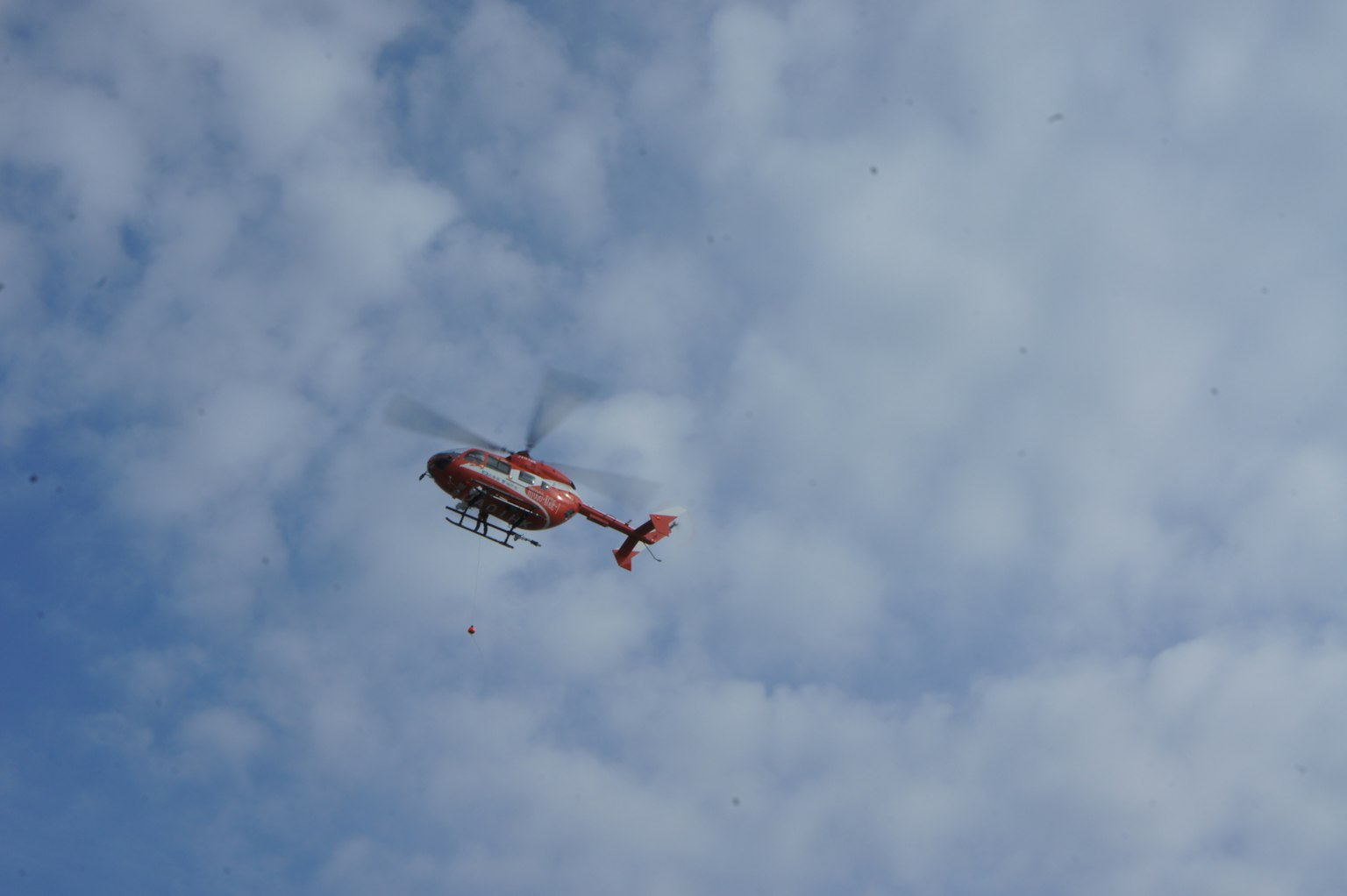 Helikopter merah terbang di langit biru