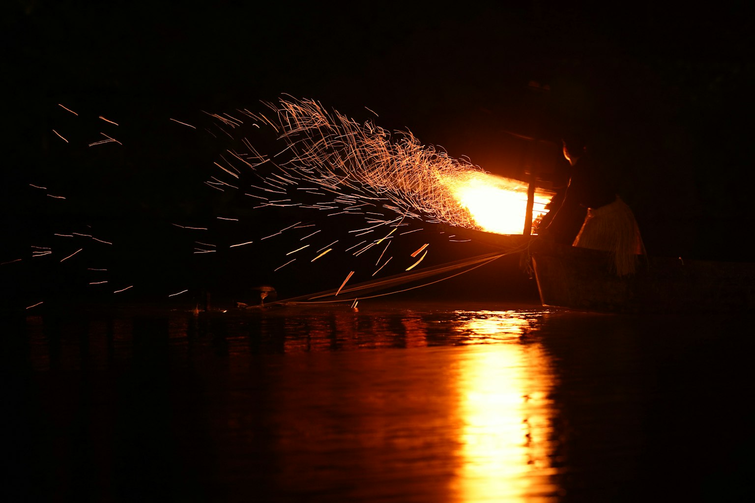 Fischerboot erzeugt Funken und Licht auf dem Wasser bei Nacht