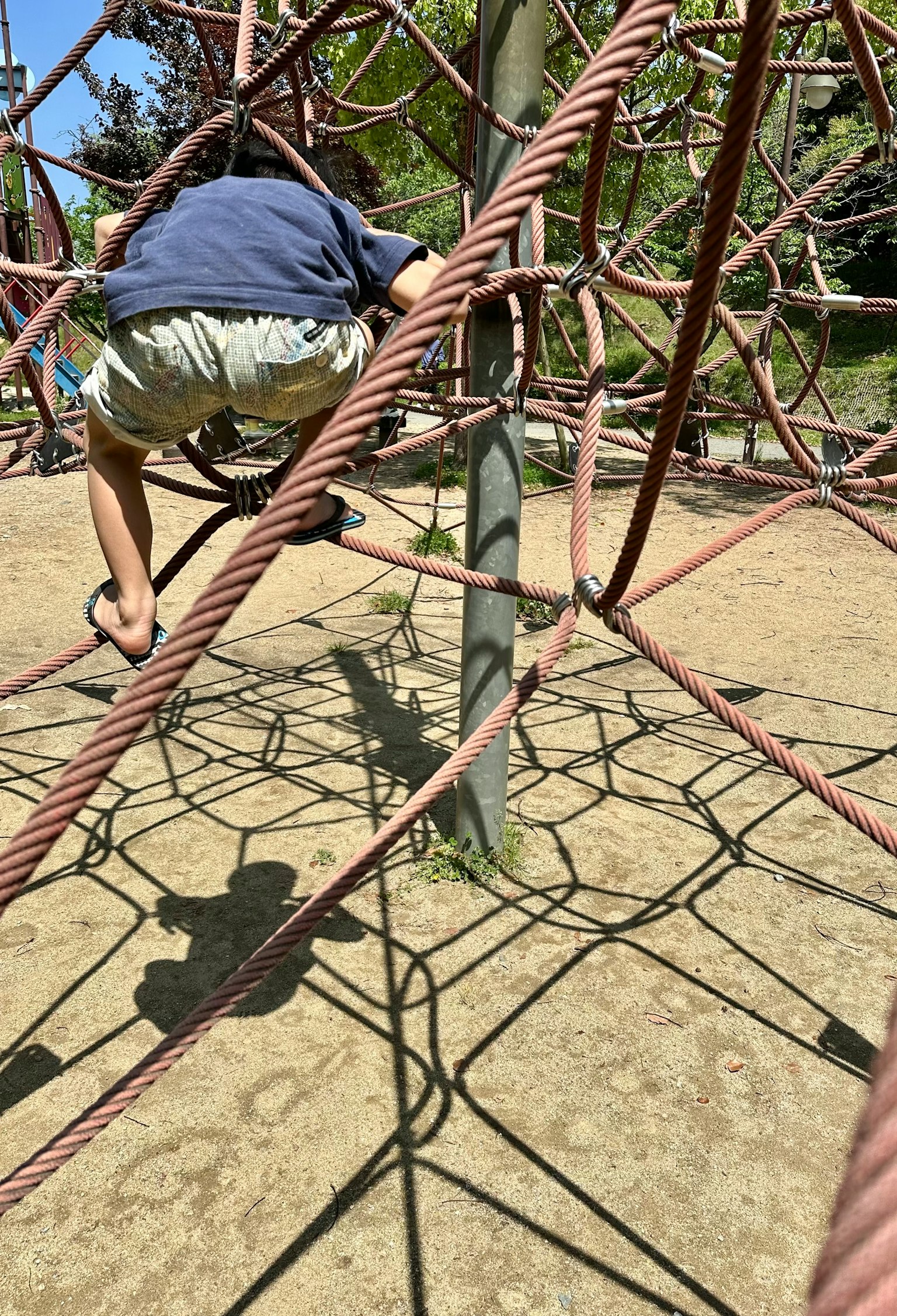 Kind klettert auf einer Seilstruktur auf einem Spielplatz