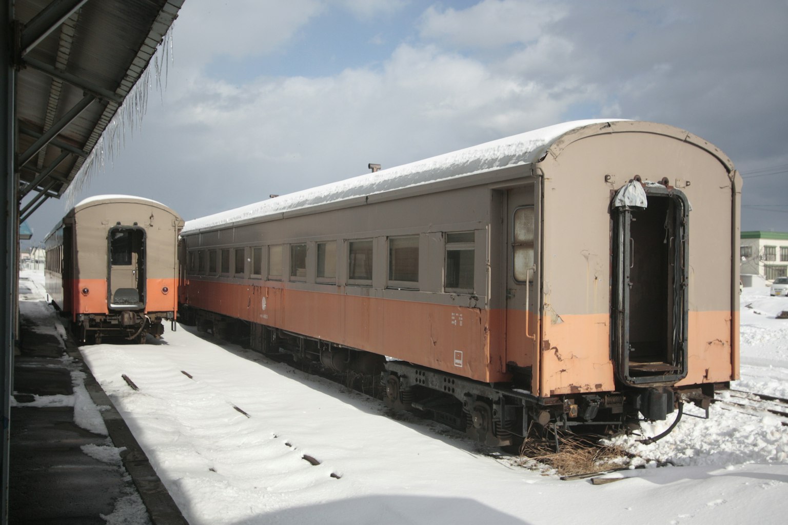Old train cars parked at a snowy station