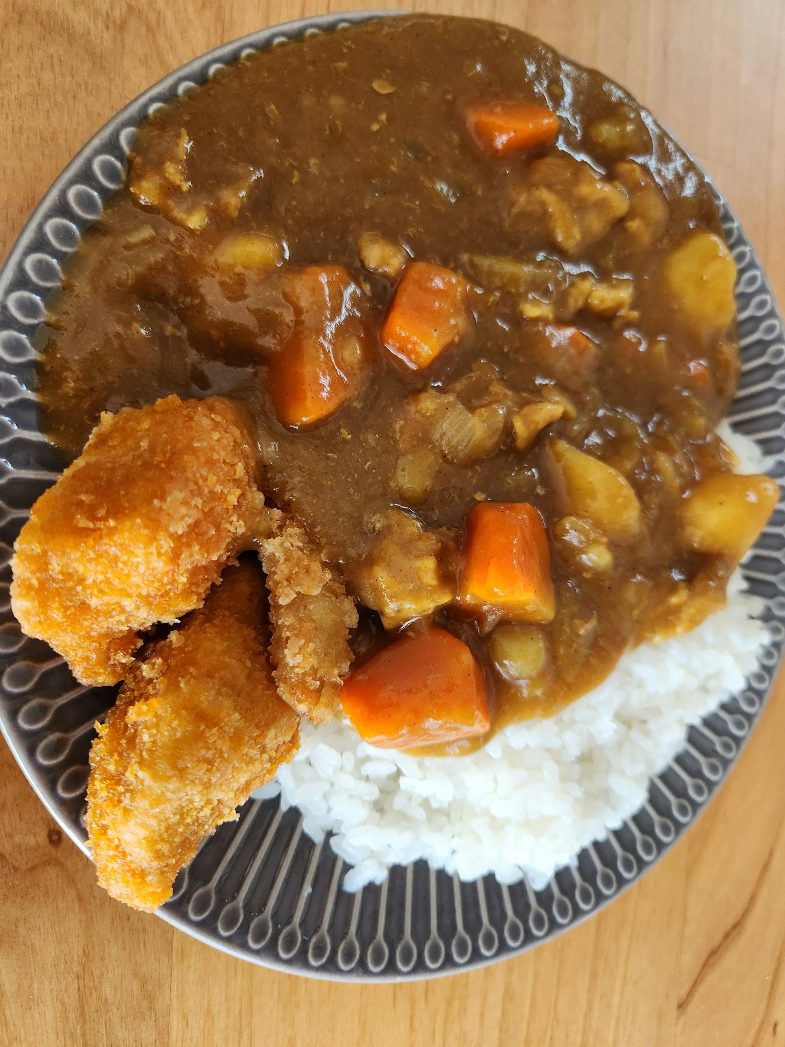 Un piatto con curry di verdure su riso bianco accompagnato da elementi fritti