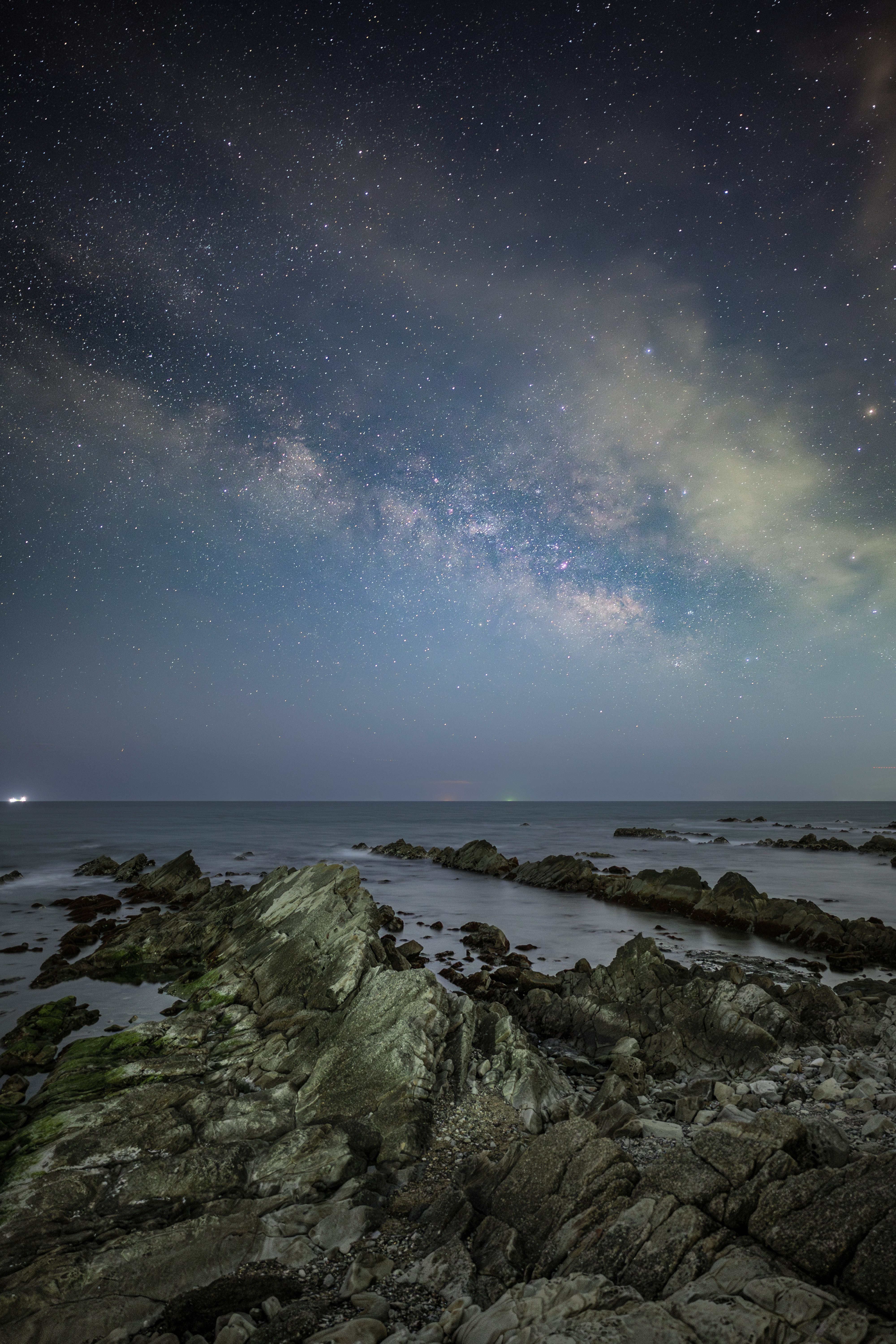 岩場の海岸に広がる夜空と天の川