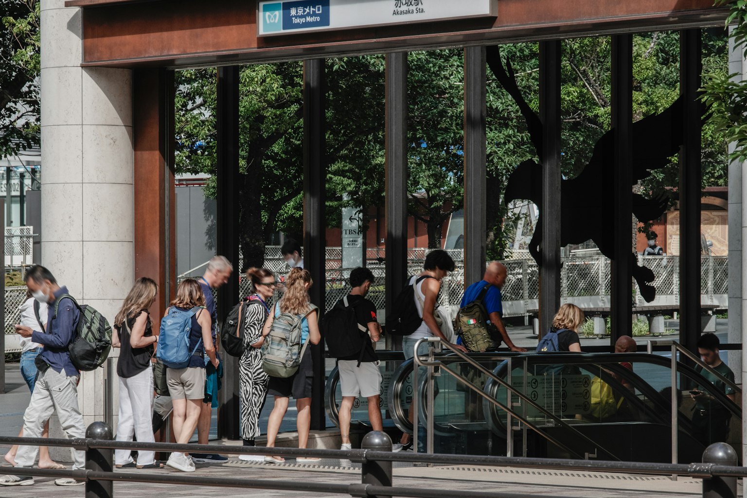 Personas esperando en la entrada de una estación de tren con vegetación de fondo