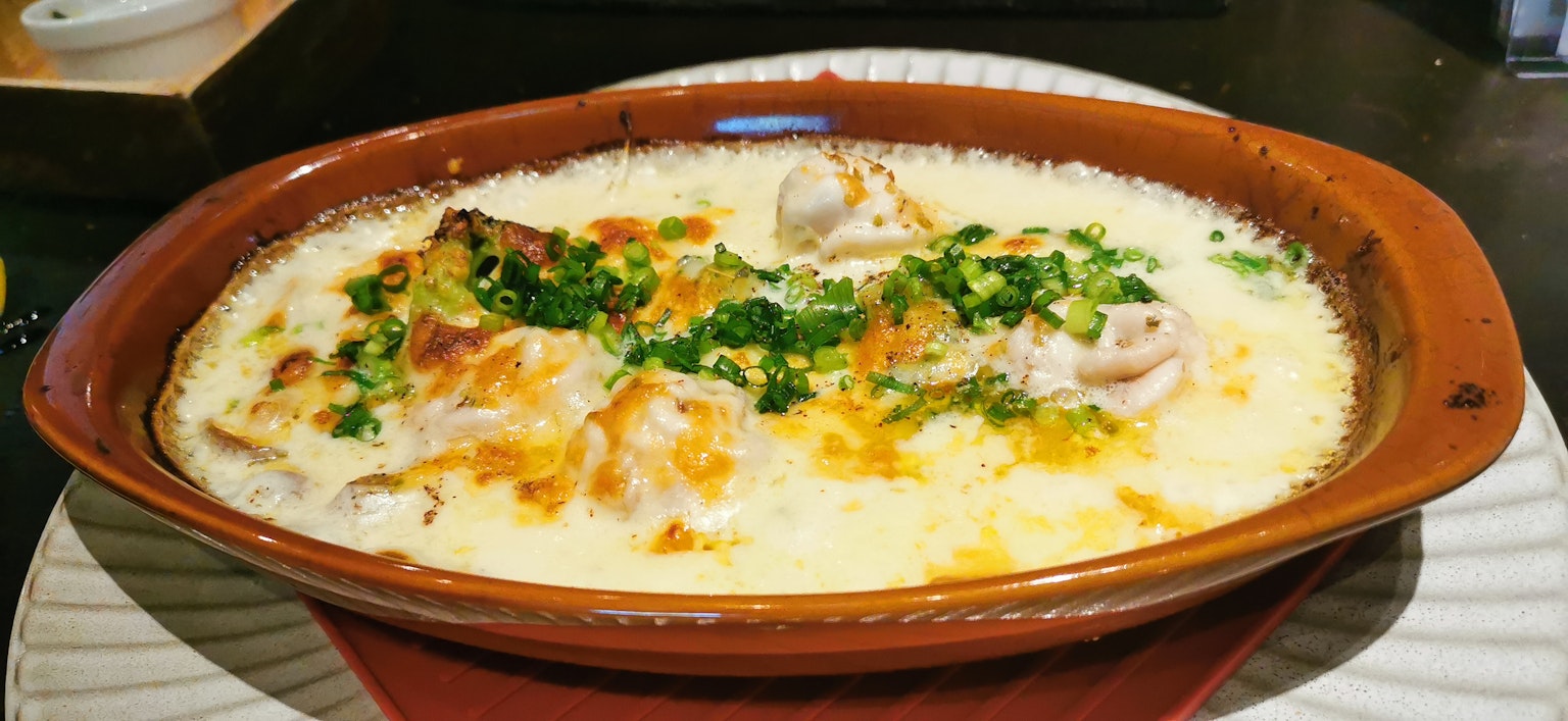 Piatto al forno con salsa cremosa e pollo dorato guarnito con erbe verdi