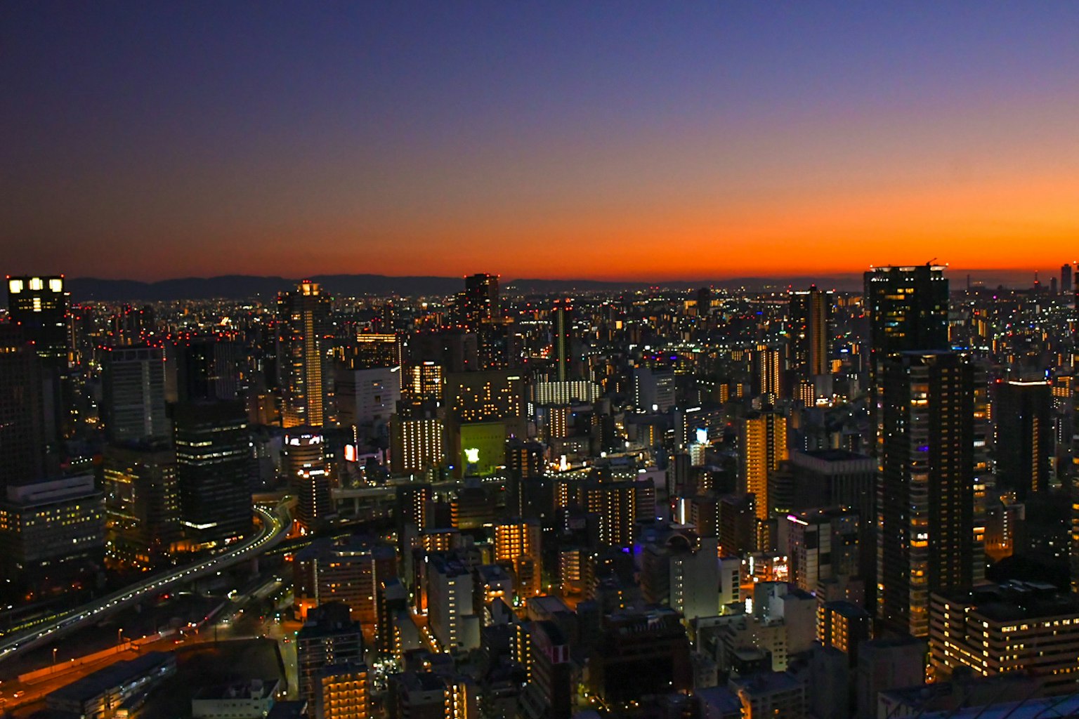 Paysage urbain d'Osaka au crépuscule avec des gratte-ciel illuminés et des lumières vives