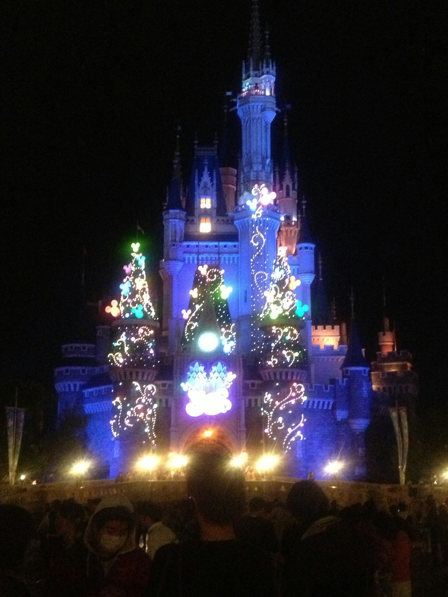 Un castillo iluminado por la noche con árboles de Navidad y decoraciones