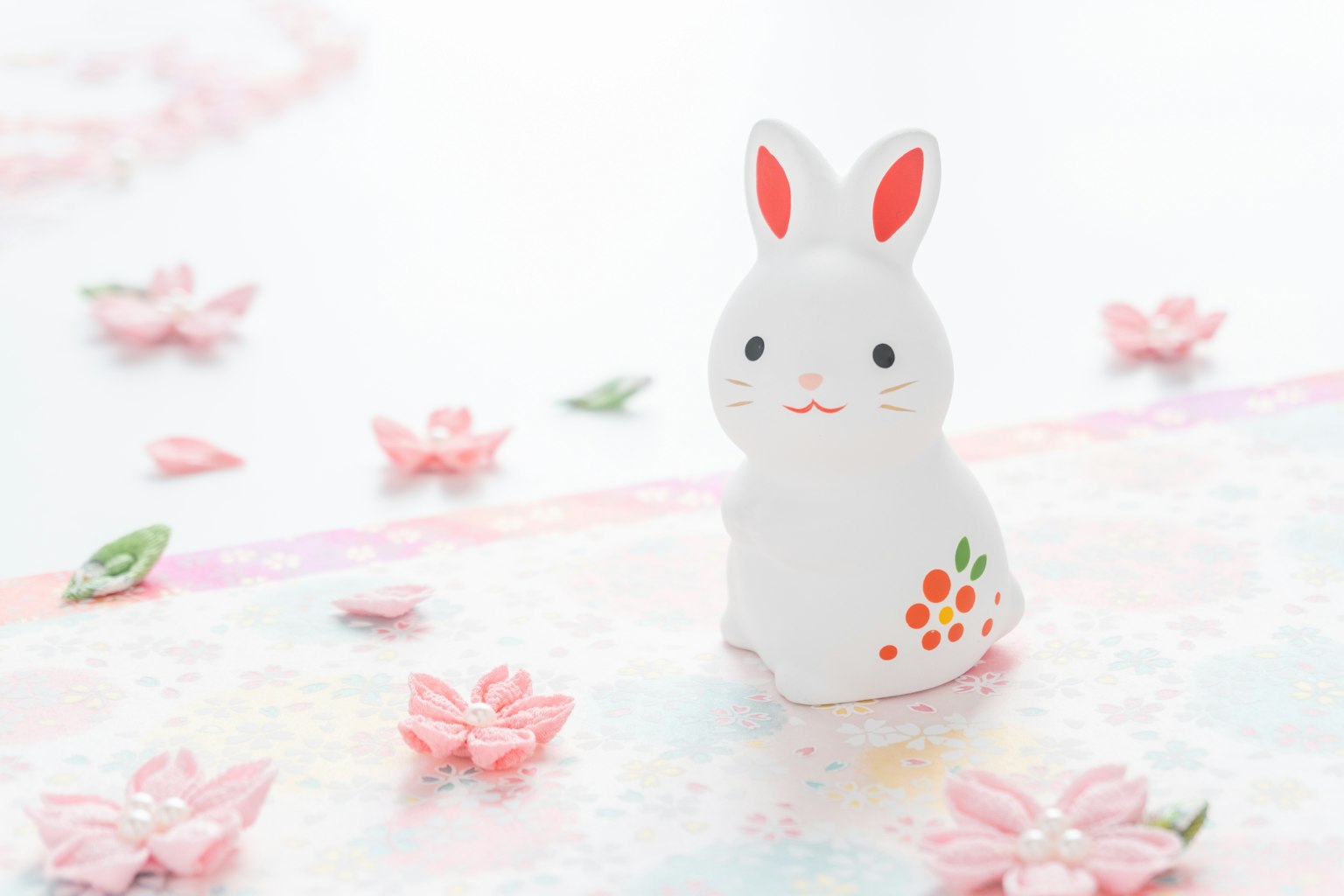 Tượng thỏ gốm trắng được bao quanh bởi cánh hoa hồng