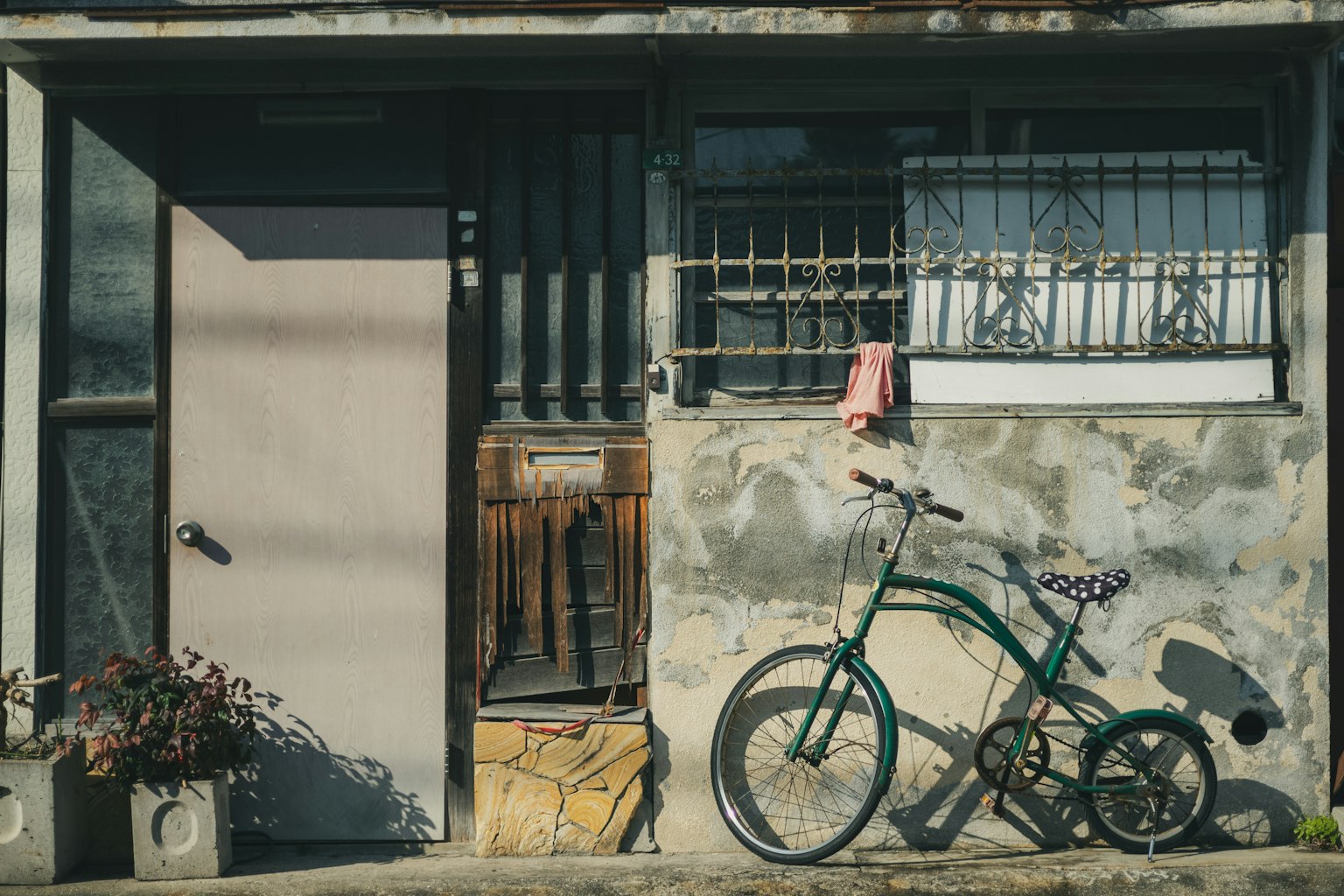 Una bicicleta verde y una caja de madera frente a una casa antigua