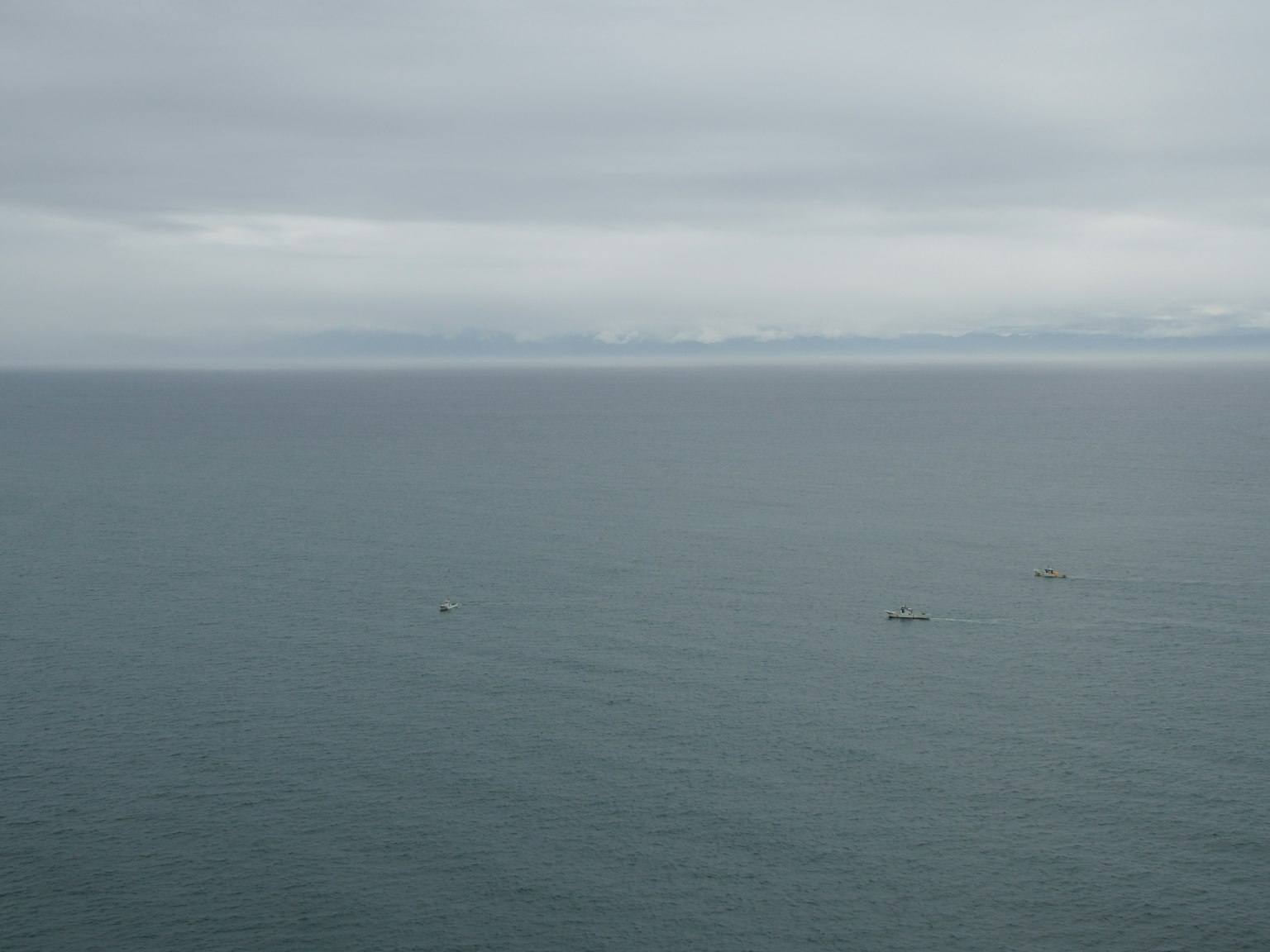 Una vista serena delle acque calme dell'oceano sotto un cielo grigio con piccole barche visibili