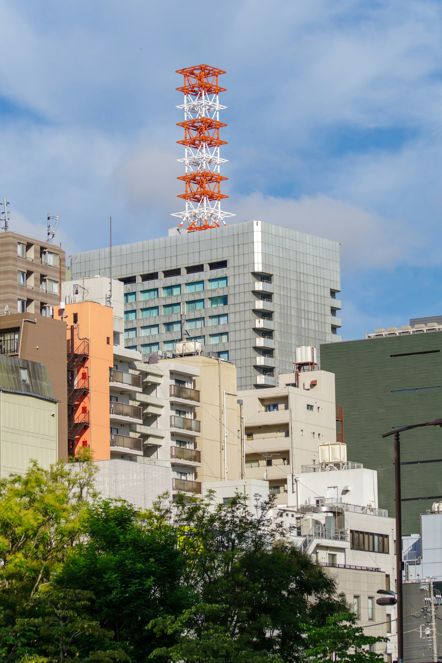 Tour de communication rouge et blanche parmi des bâtiments urbains à Tokyo