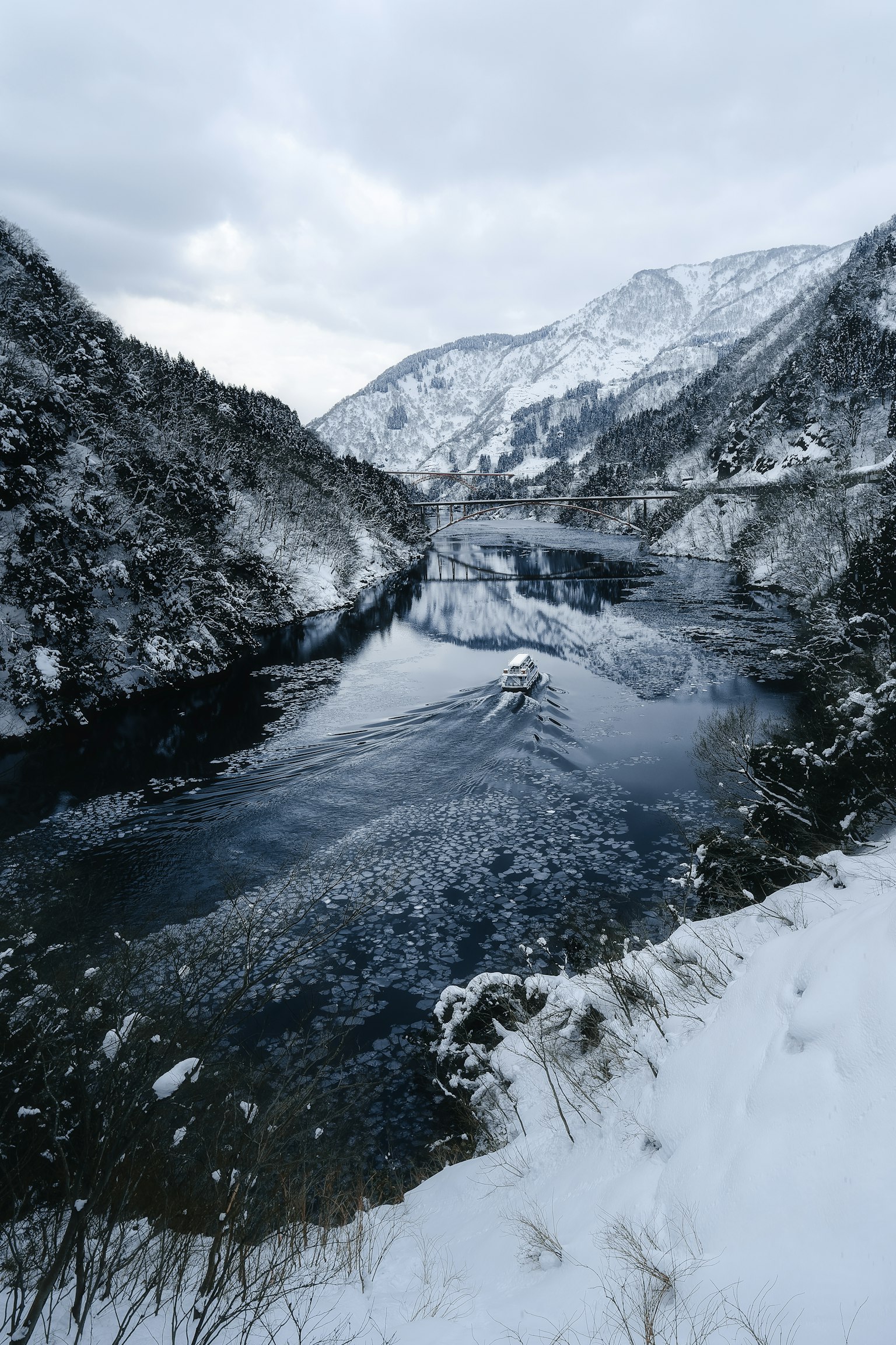 Une rivière tranquille coulant entre des montagnes enneigées