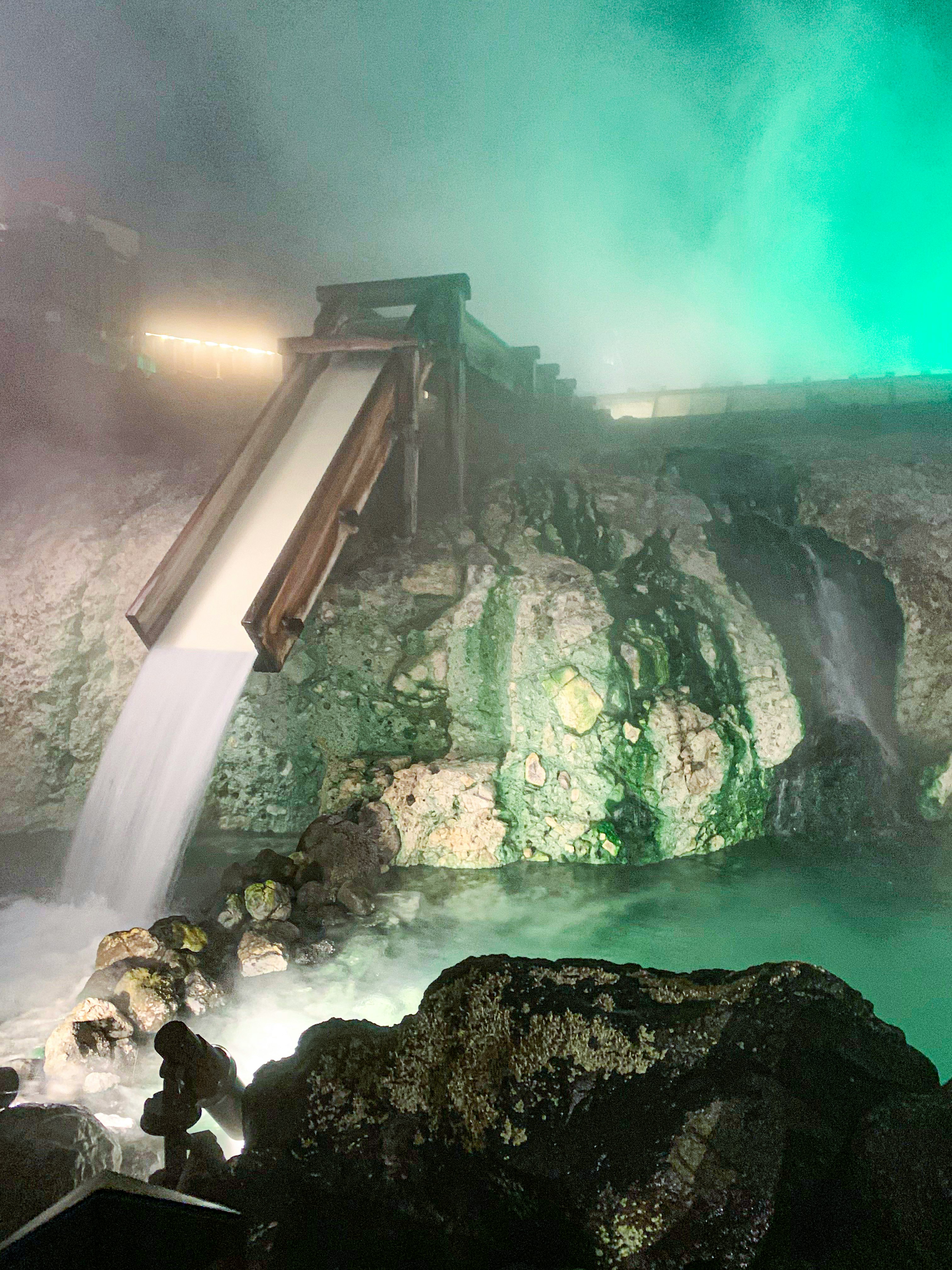 espace de grotte avec une fontaine en cascade éclairée en vert et bleu