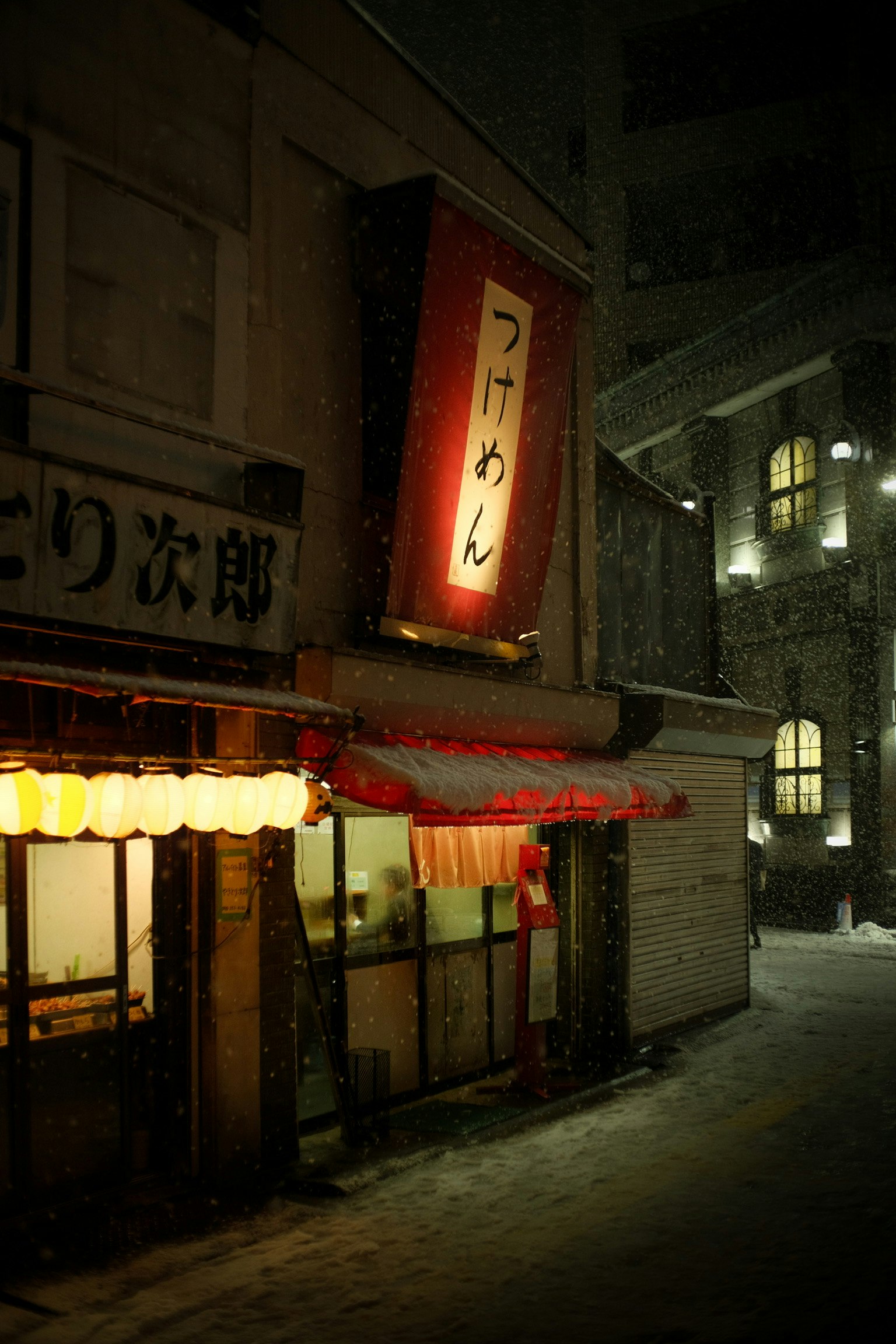 雪中的拉麵店外觀紅色招牌和發光的燈籠