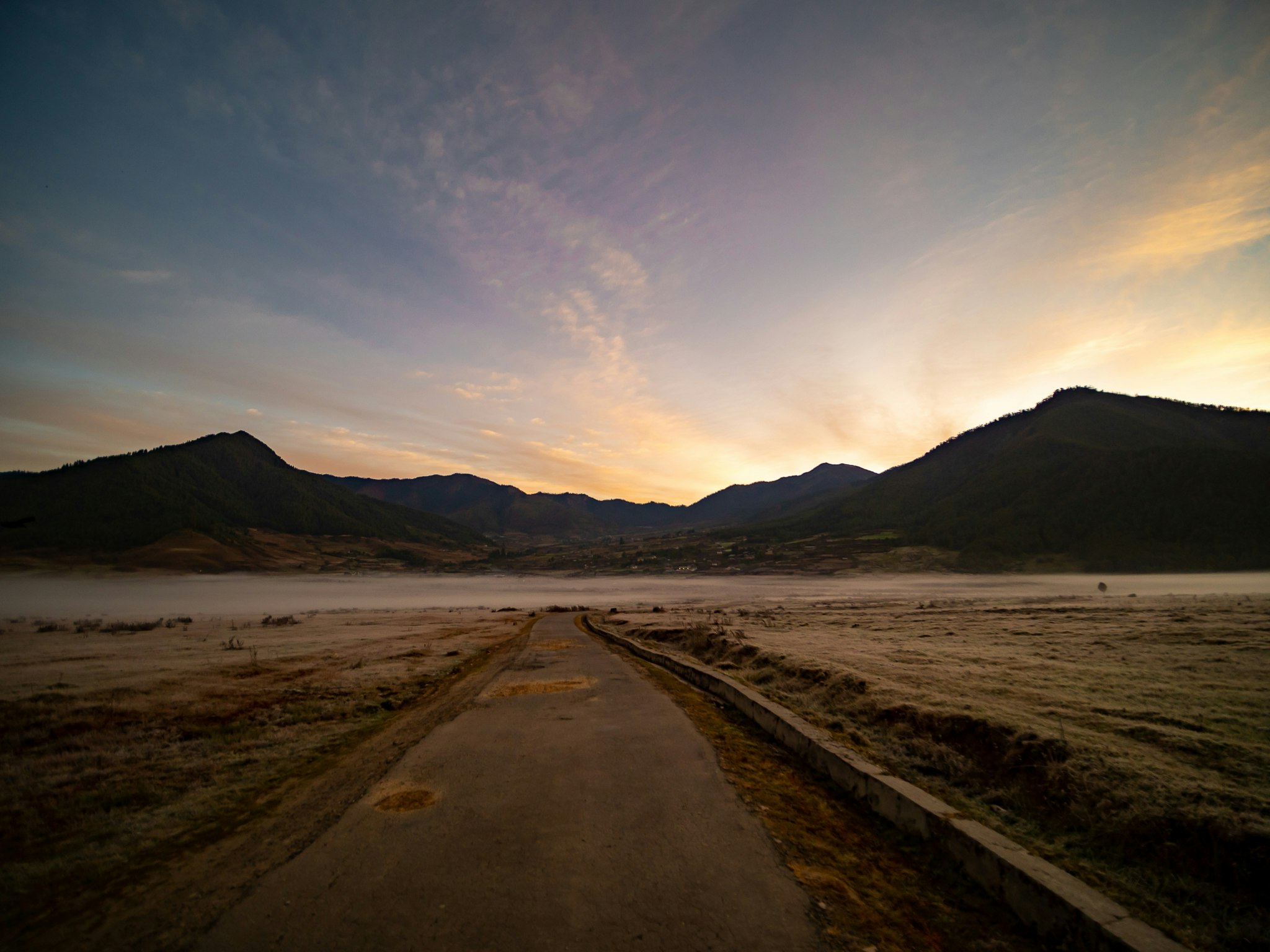A straight road through a desert at dusk