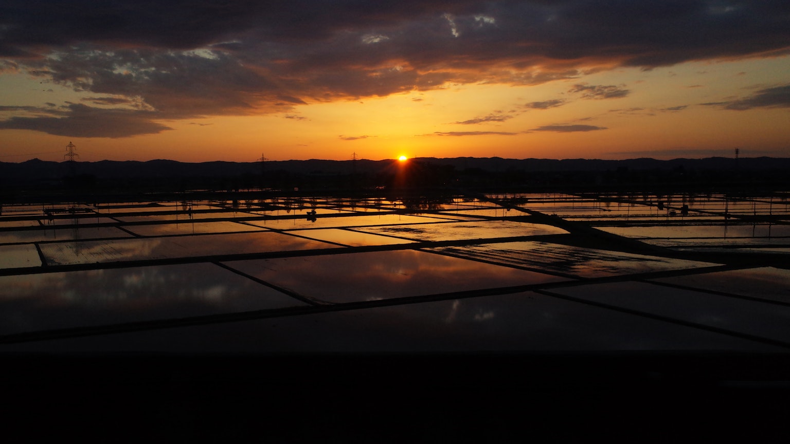 Matahari terbenam di sawah reflektif