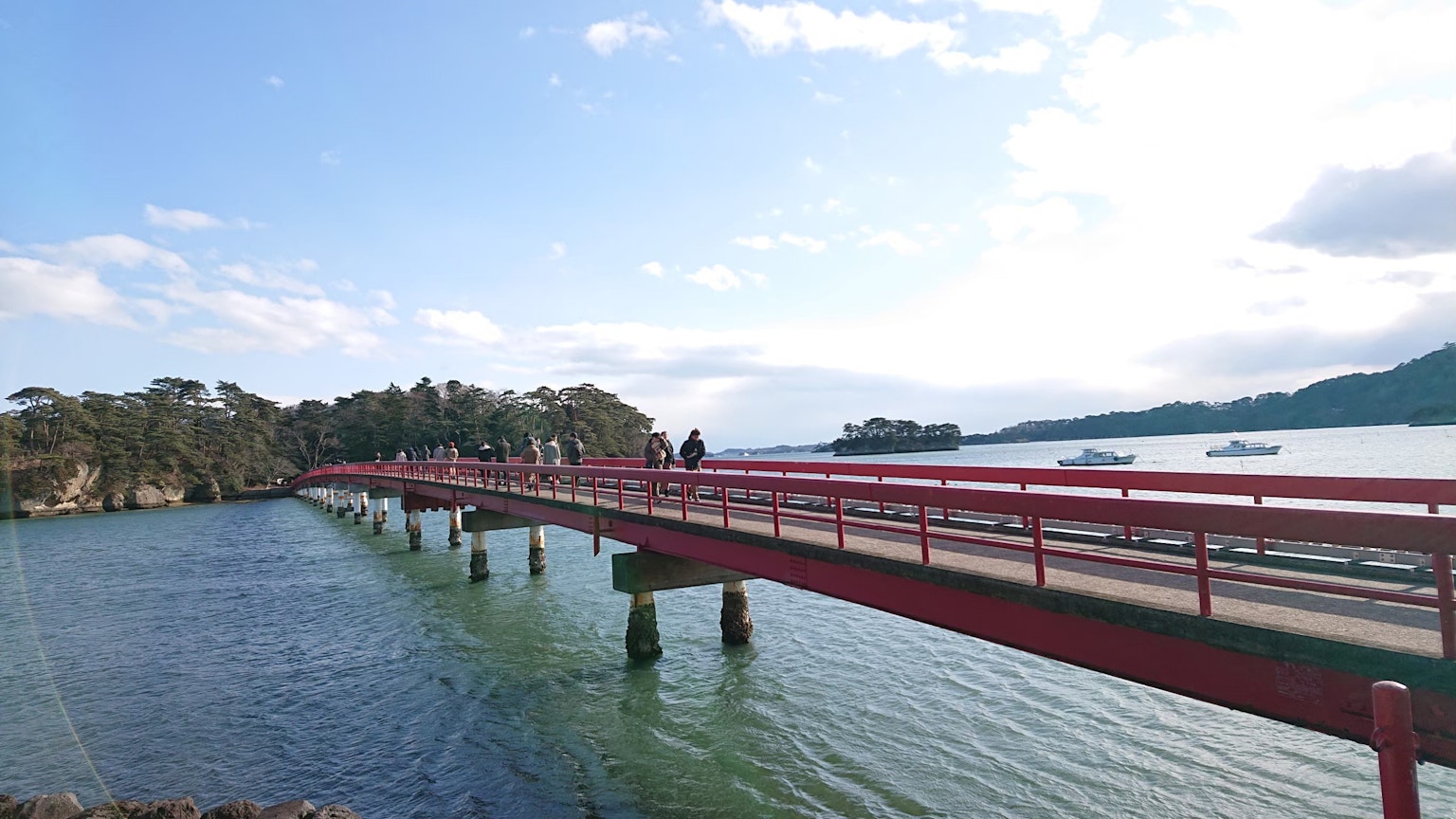 一座红色桥梁横跨水面，周围环绕着自然风光
