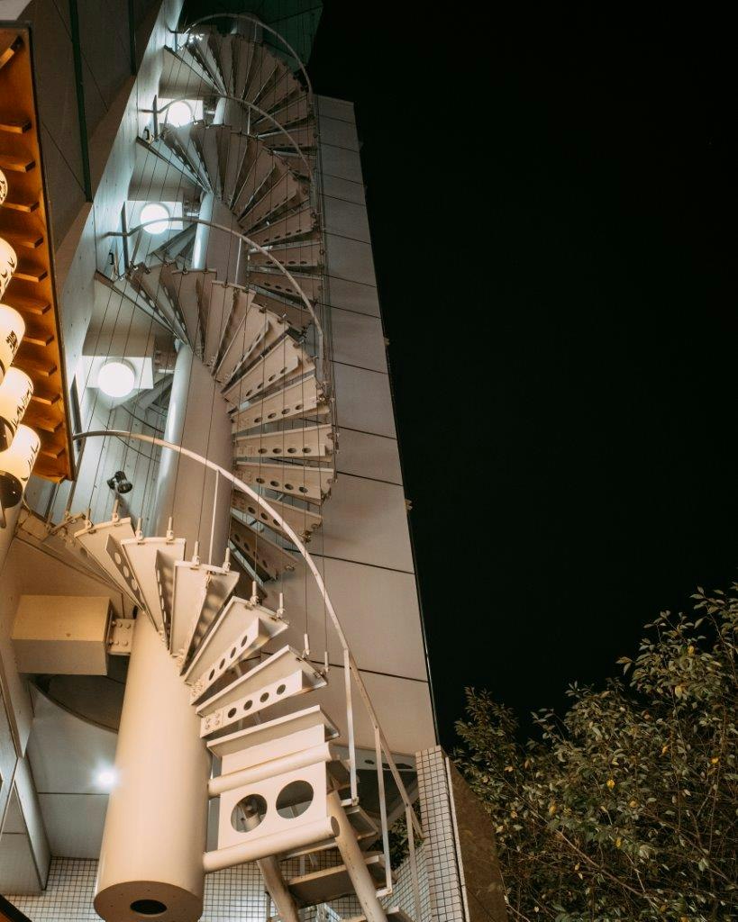 escalier en colimaçon le long d’une façade de bâtiment la nuit