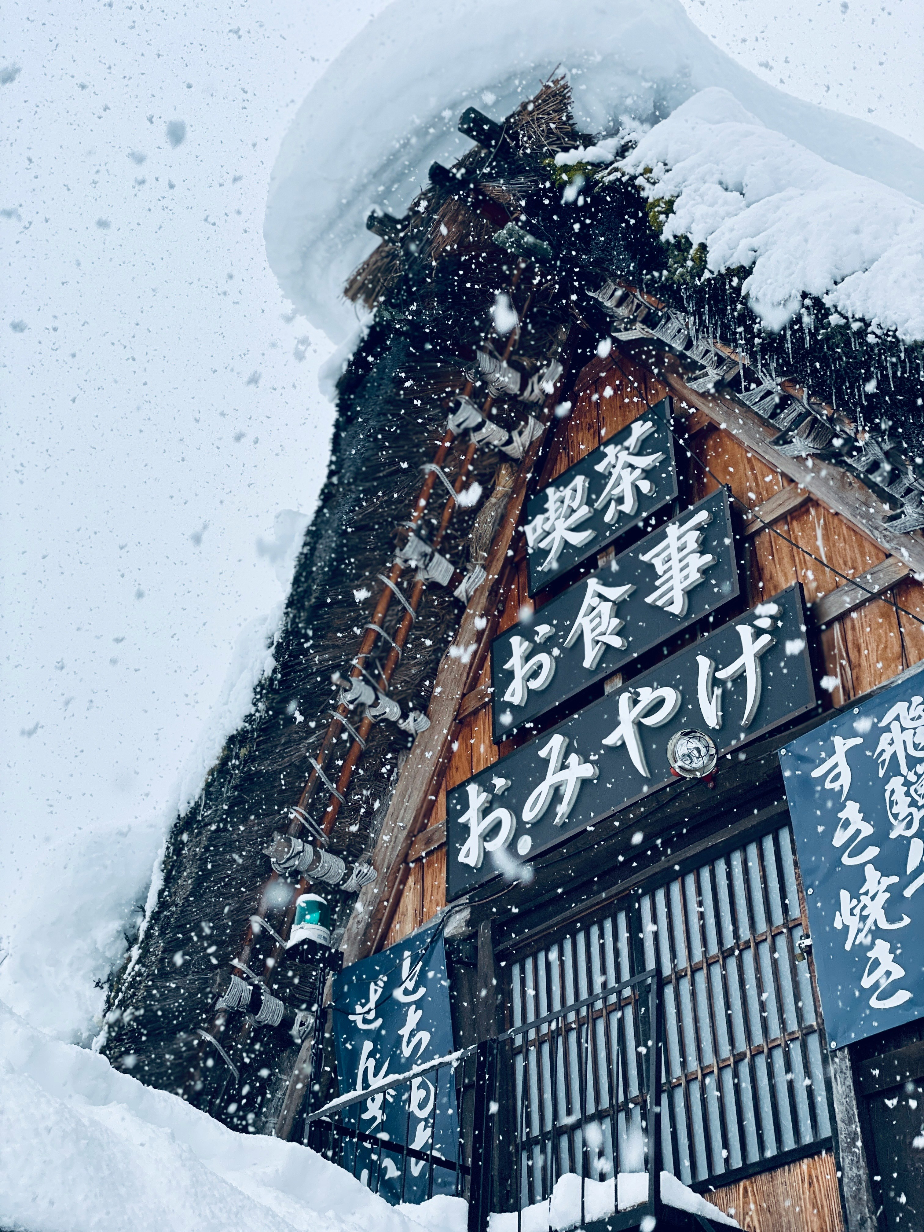 雪が降る合掌造り風の看板建物の外観