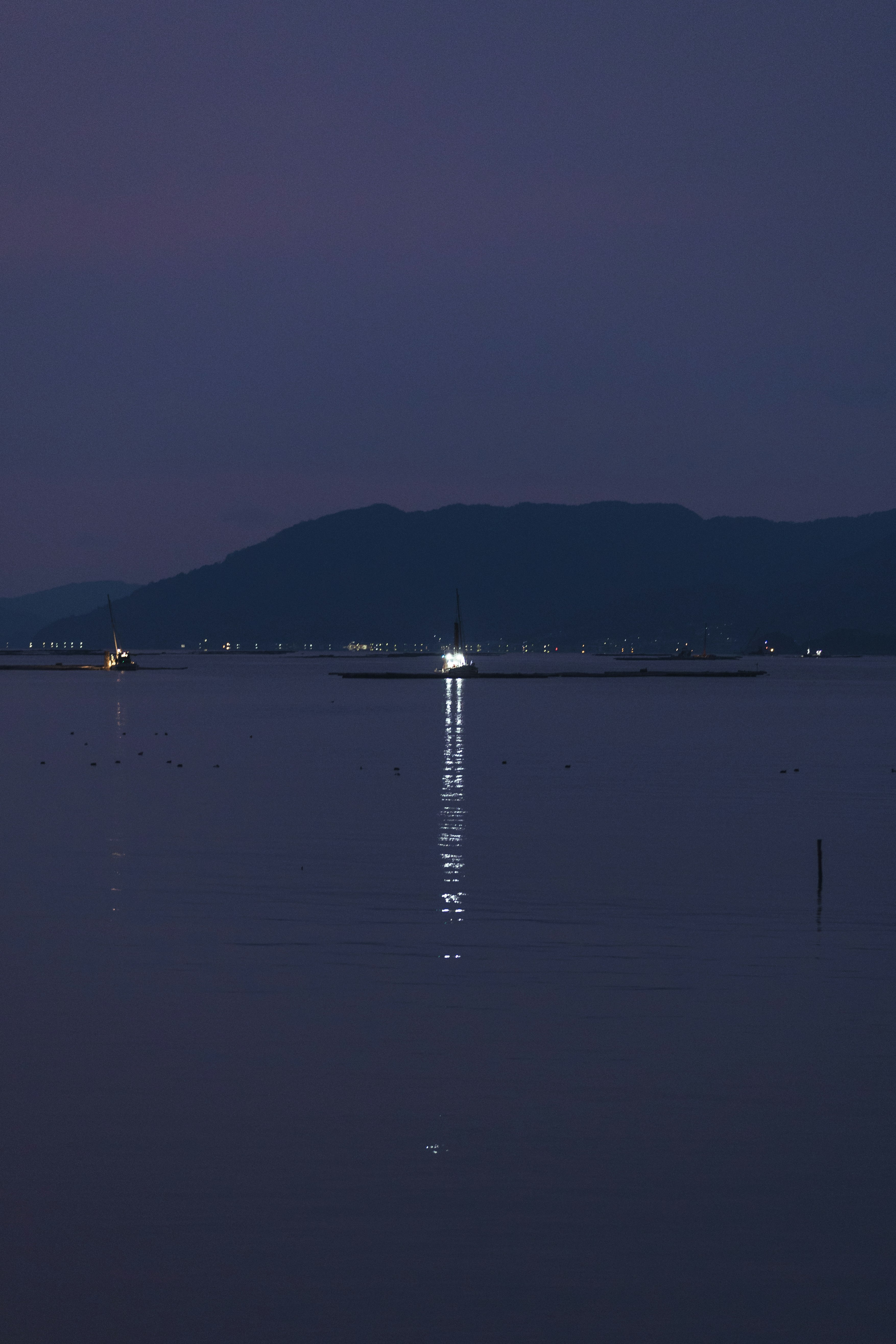夕暮れの湖面に浮かぶ桟橋と灯りのある岸辺