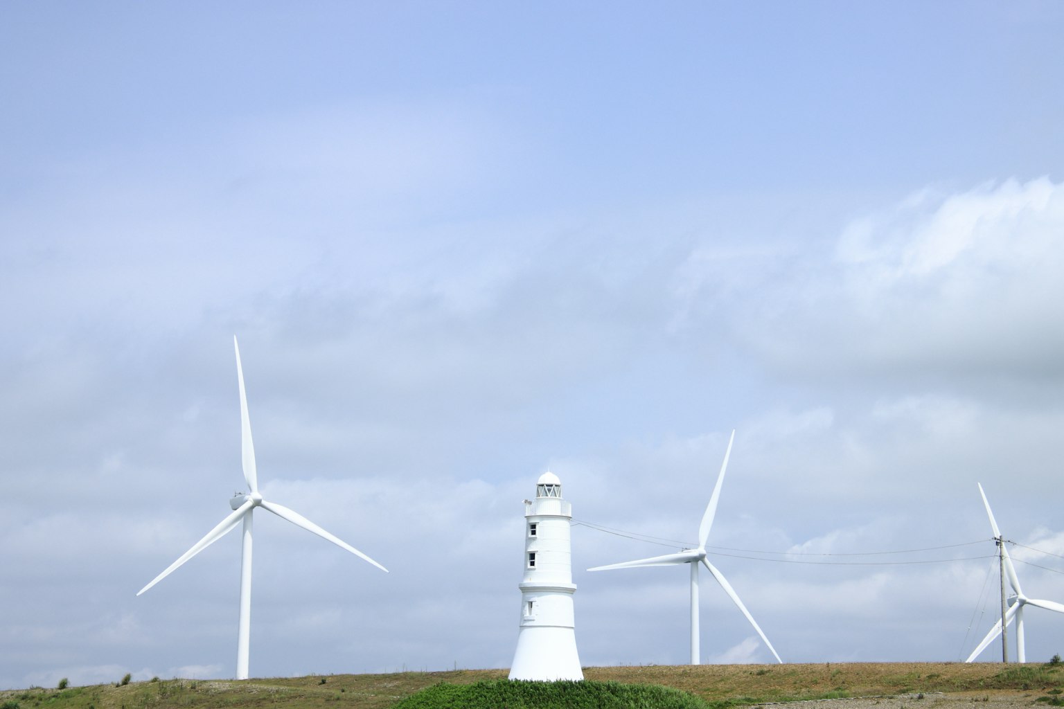 Paesaggio con turbine eoliche e un faro bianco