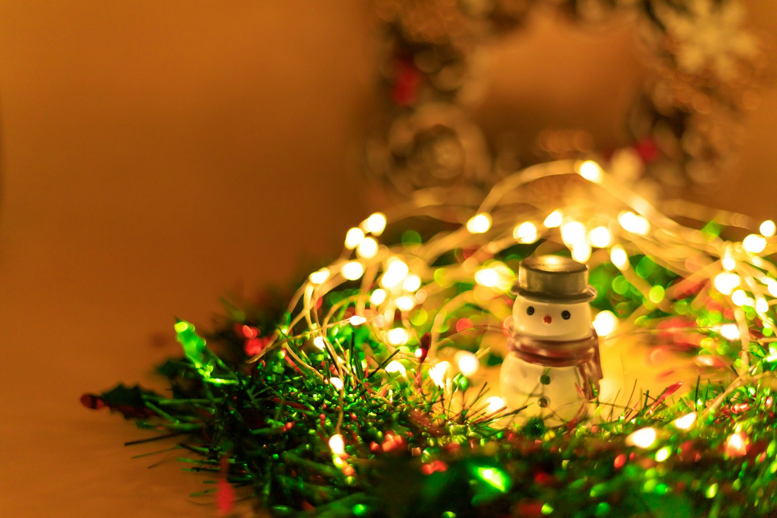 Dekorasi kecil manusia salju dikelilingi oleh lampu yang bersinar untuk Natal