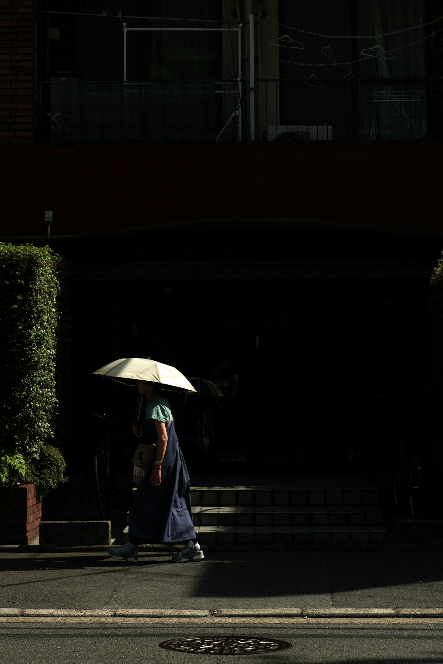 Silhouette d'une femme marchant avec un parapluie dans une rue de la ville