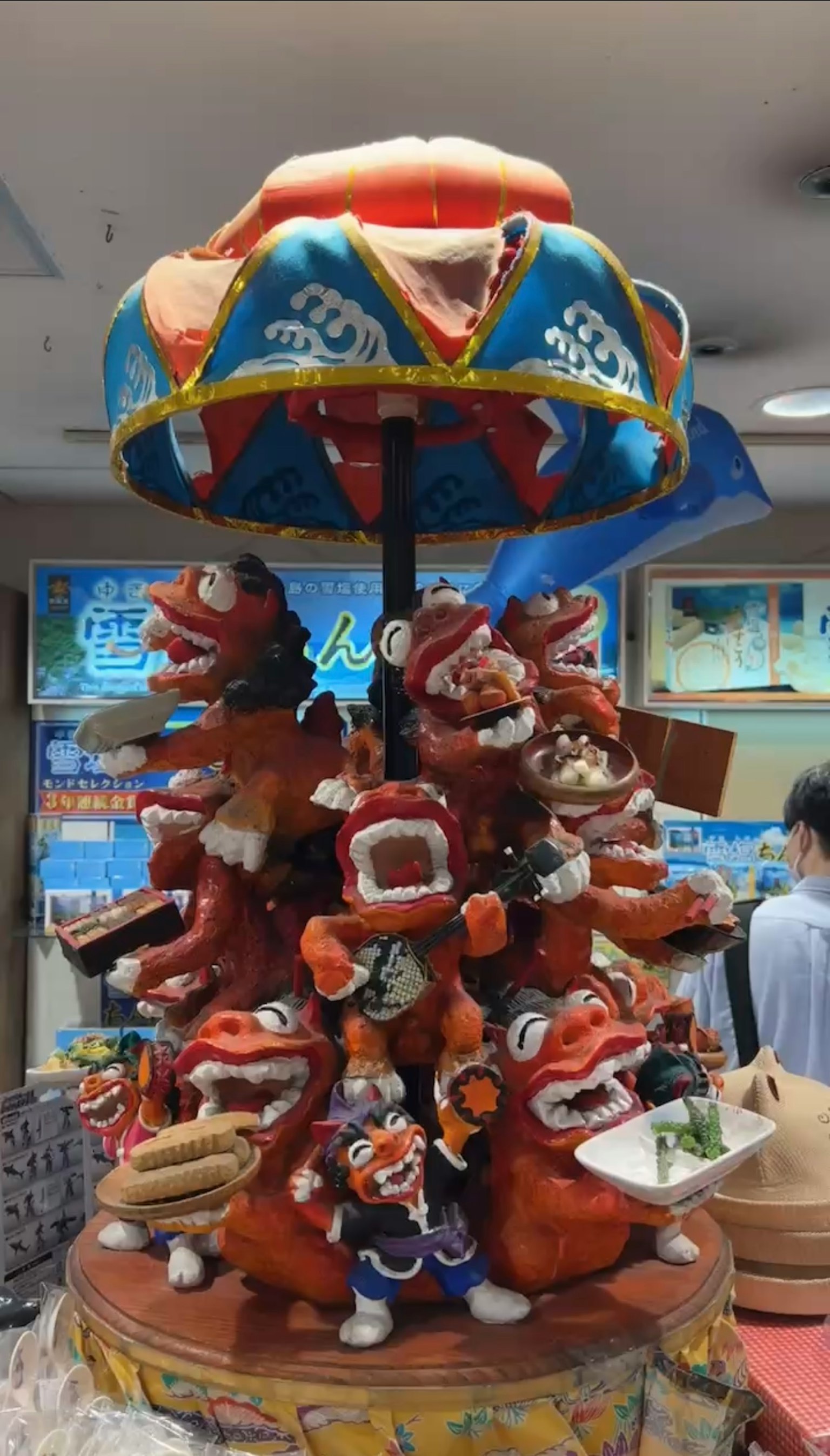 Ornamen keramik berwarna-warni dengan berbagai figur ceria di atasnya dihiasi dengan payung dekoratif
