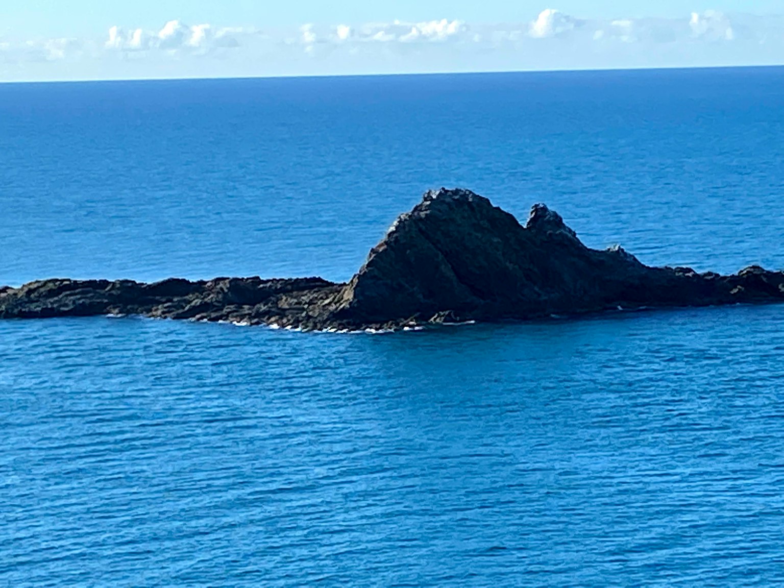 从生动蓝色海洋中冒出的岩石岛屿