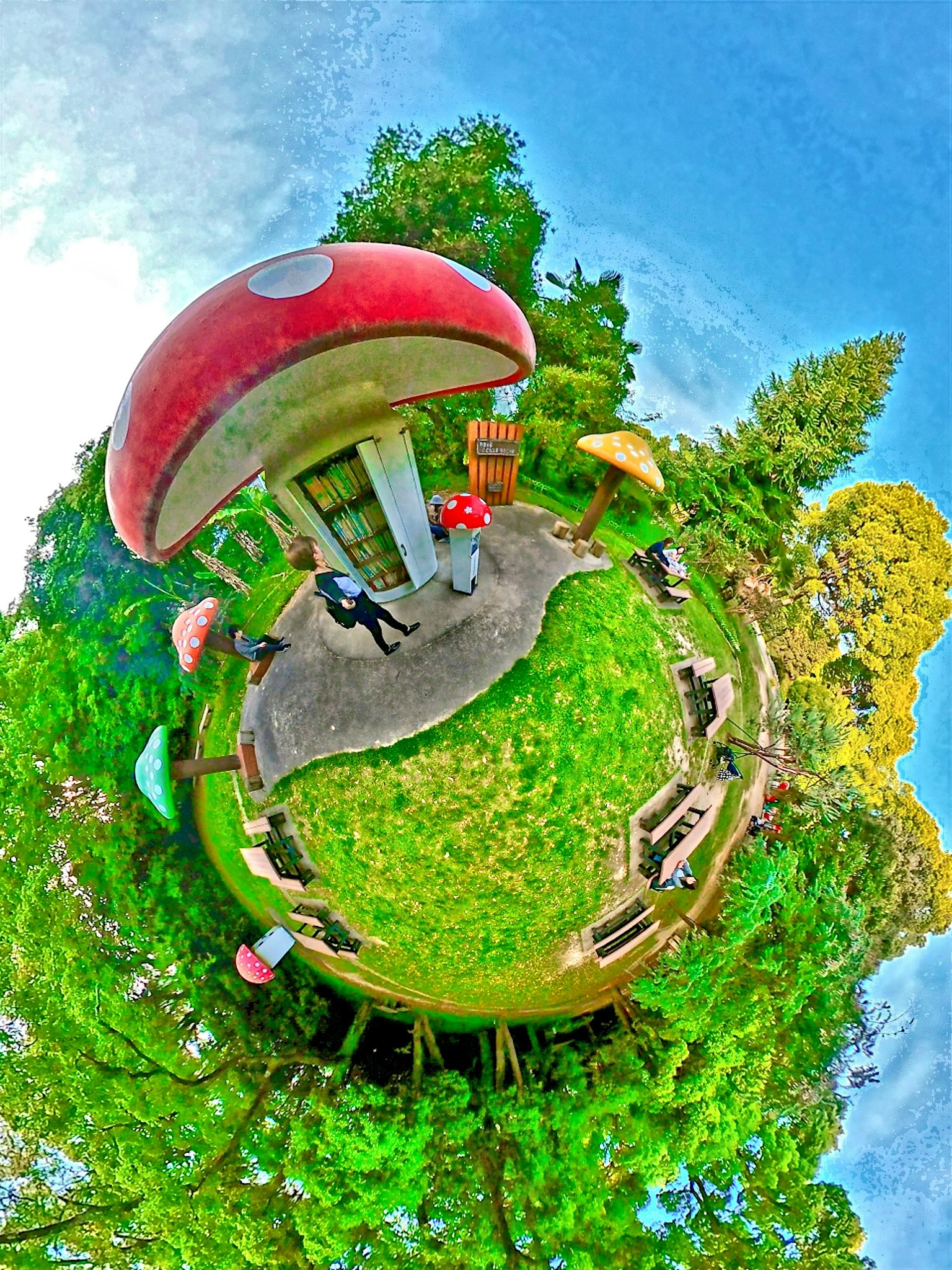 公園場景，紅色蘑菇形小屋被綠色草坪和樹木環繞