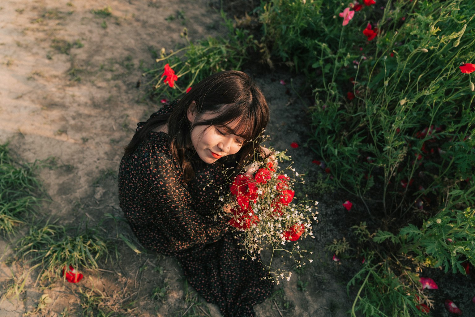 A woman smiling while holding a bouquet of flowers in a field