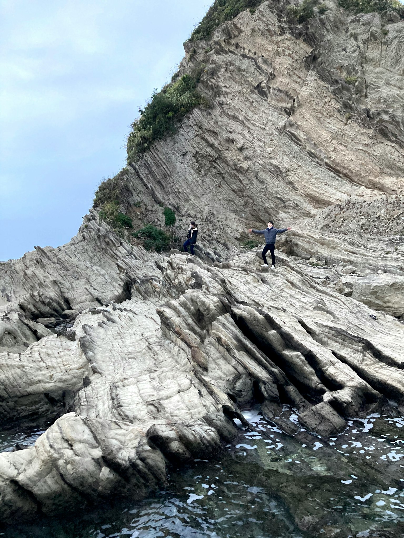 人们在陡峭悬崖的岩石海岸上行走