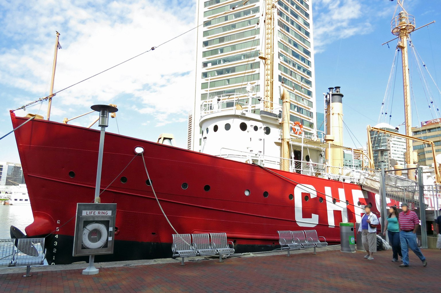 A red ship docked at the harbor with surrounding buildings and people