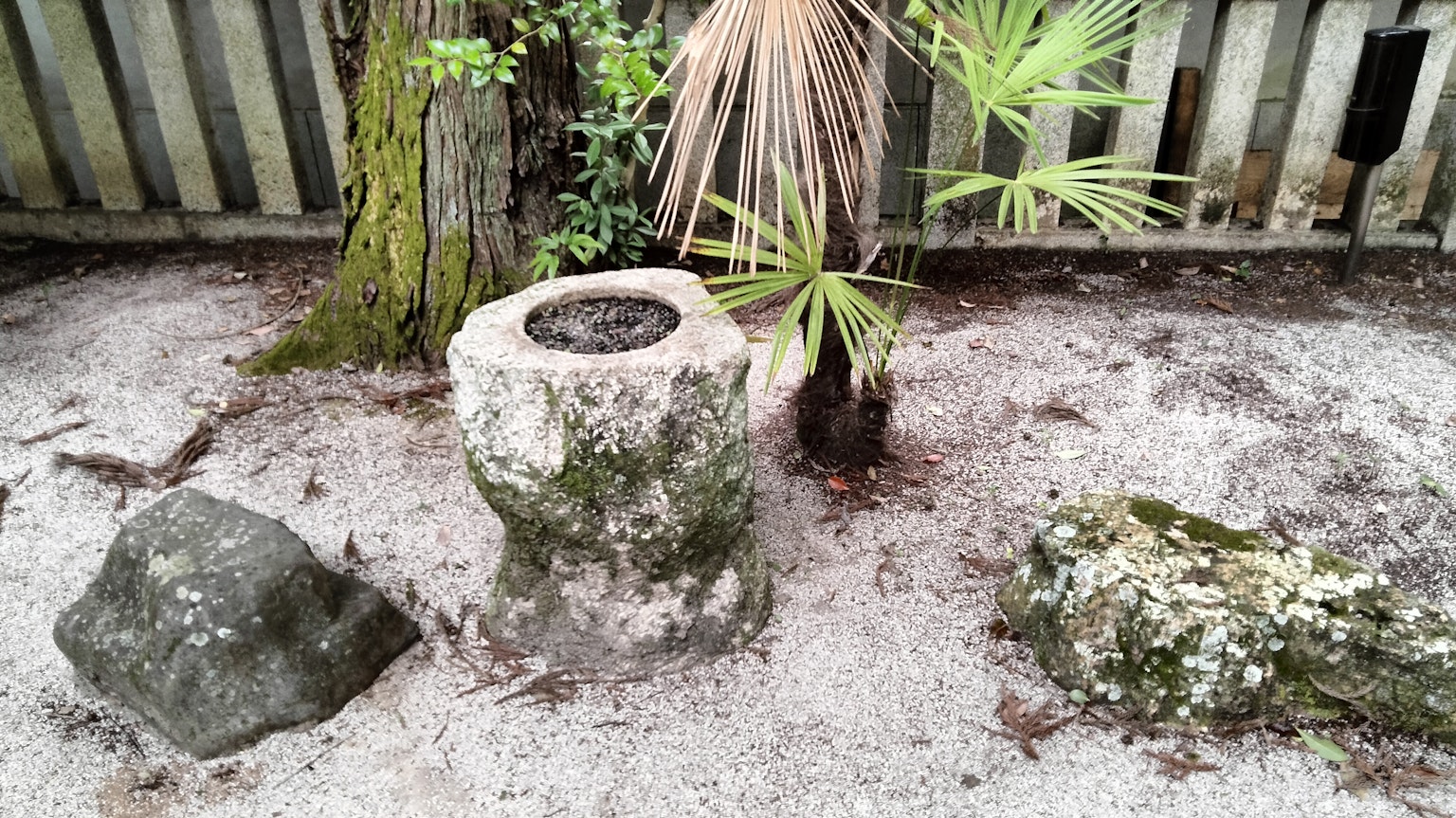 Stone pedestal surrounded by gravel and plants