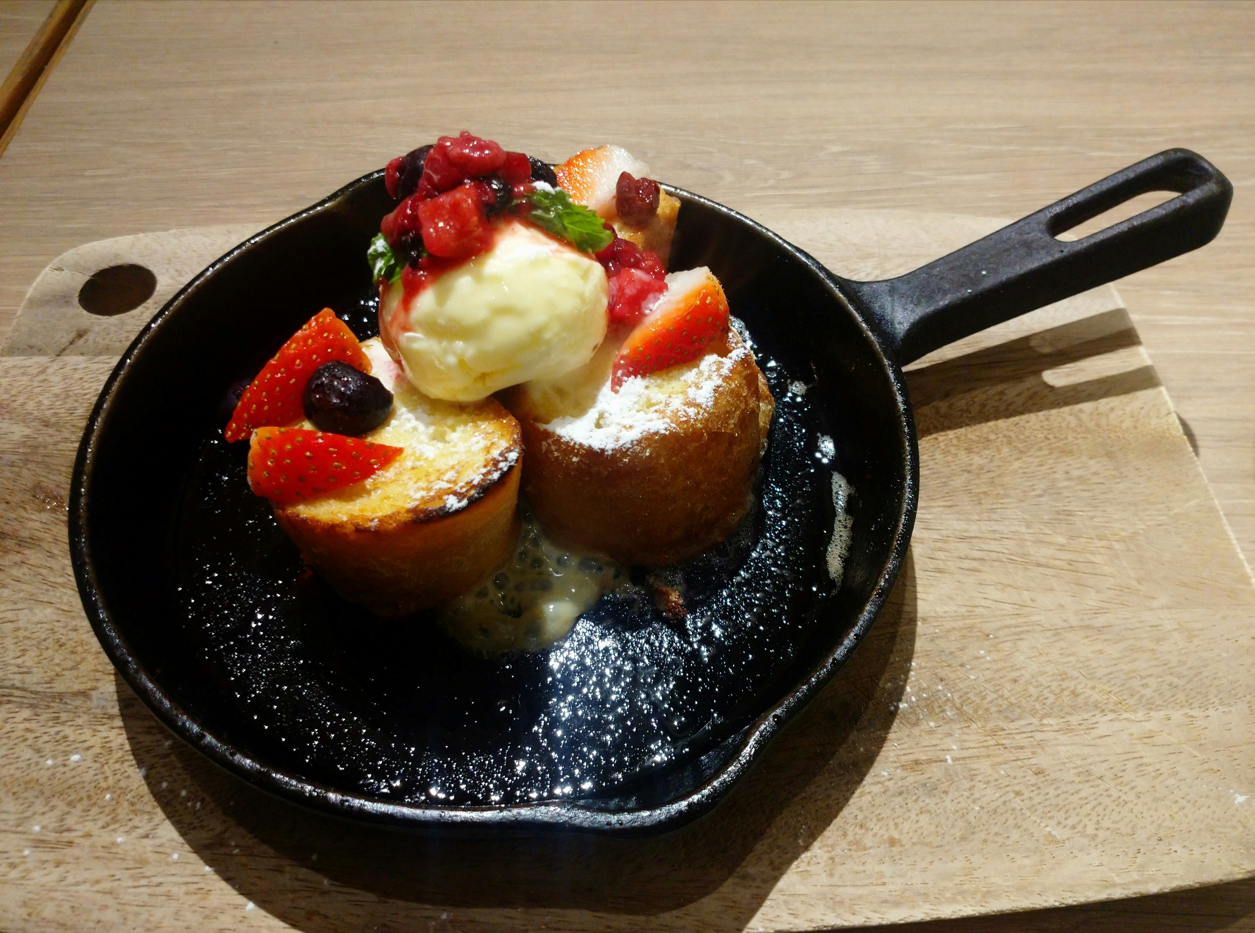 French toast topped with berries and ice cream in a skillet