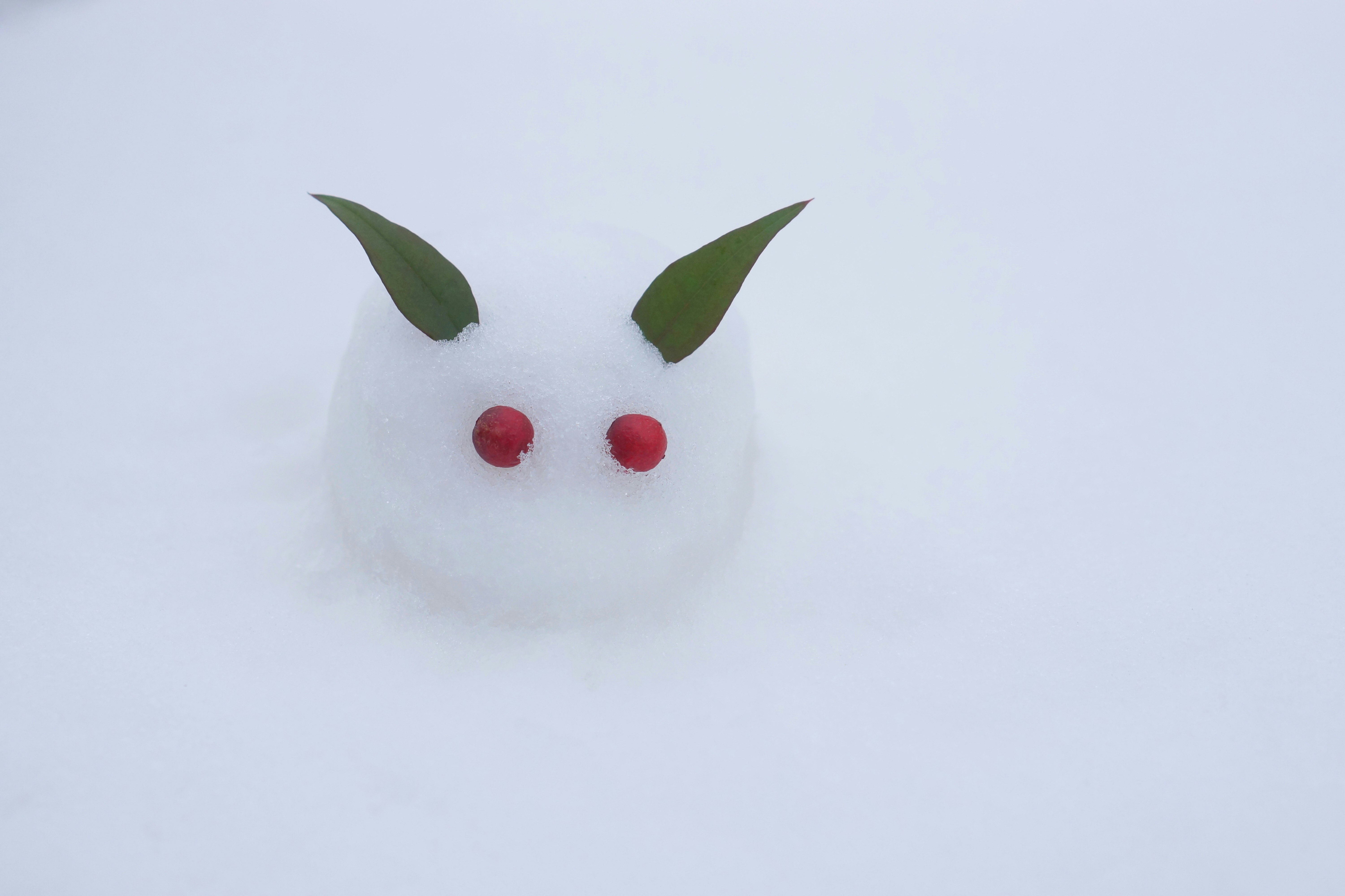 雪の上に置かれた白いふわふわの雪だるま風マスコット