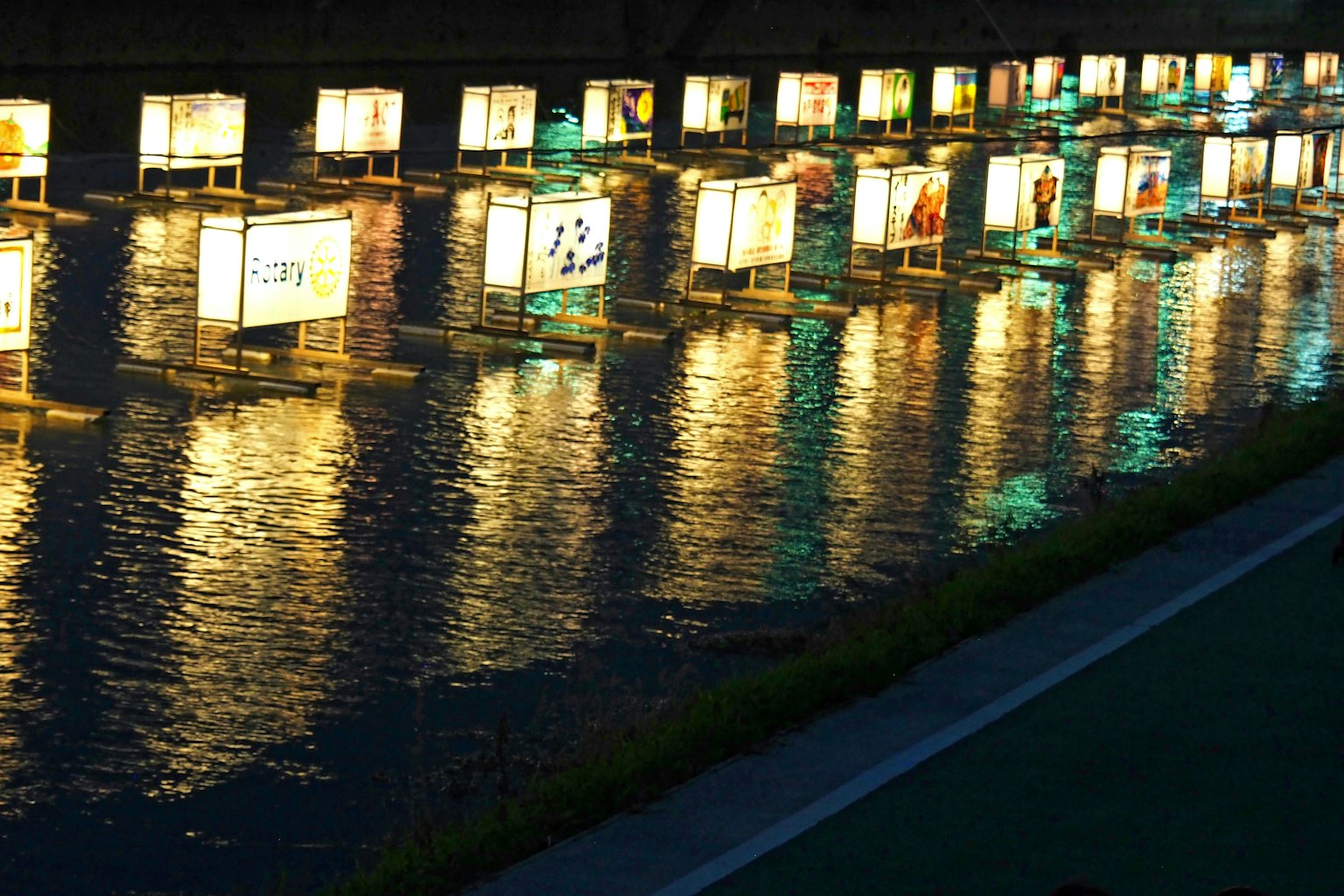 Pannelli illuminati che galleggiano su un fiume di notte riflettendo la luce