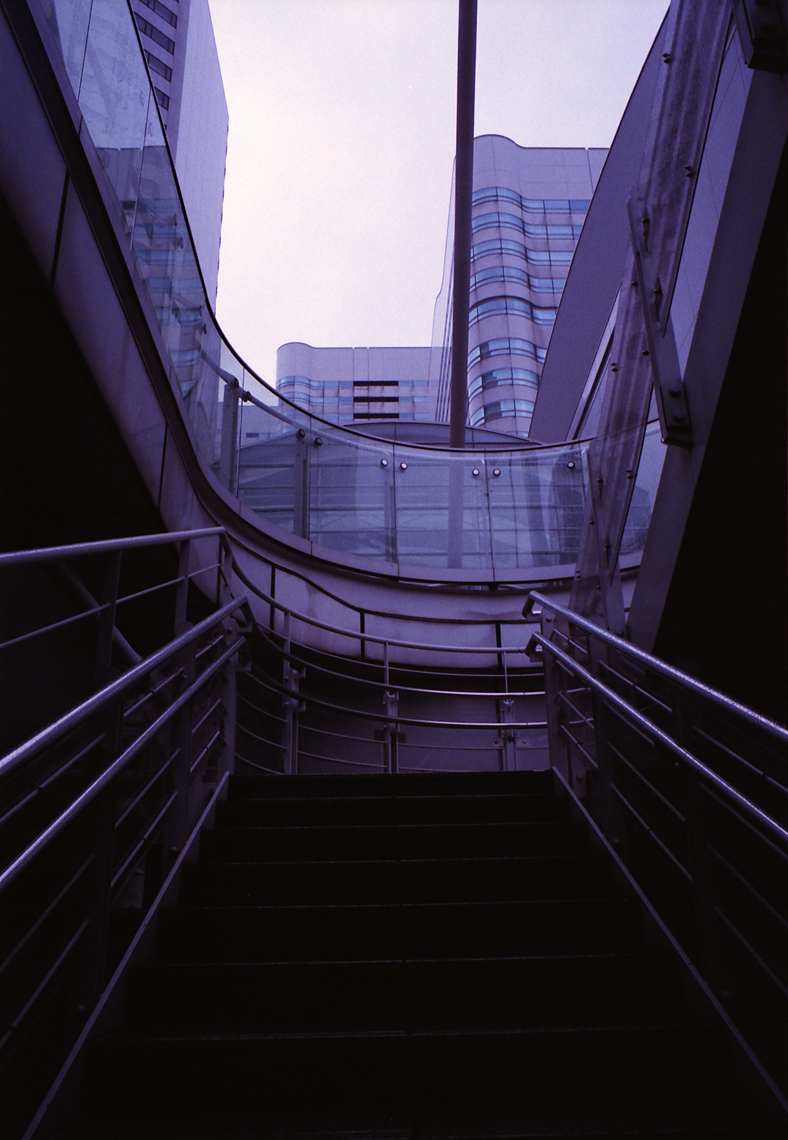 Blick von unten auf eine Treppe in einem modernen Gebäude mit Glas- und Metallgeländern