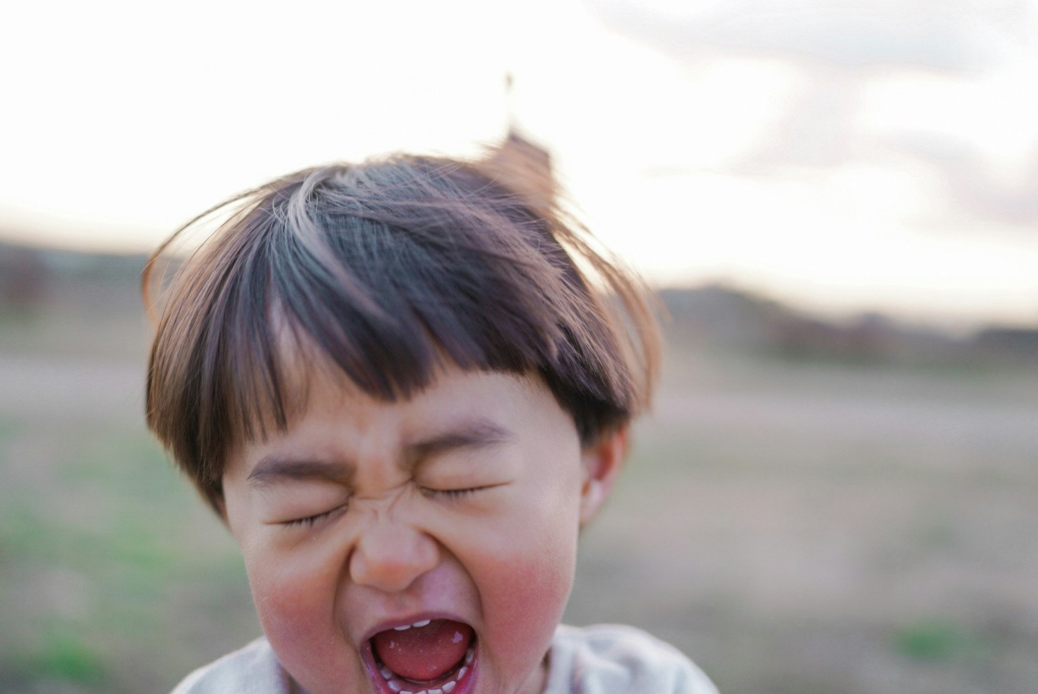 男の子が大きな声で叫んでいる笑顔の表情背景にはぼんやりとした風景