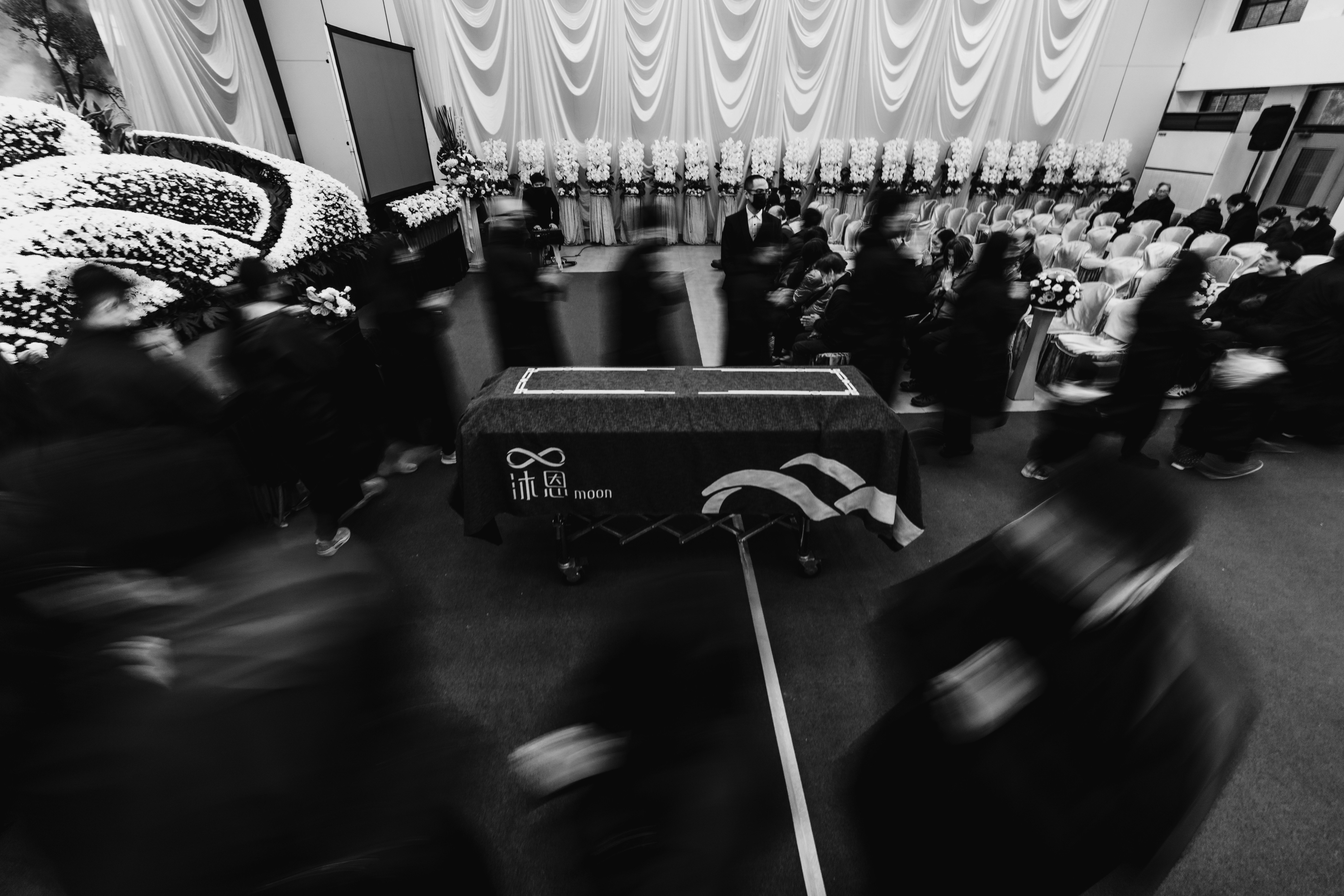黒と白の葬儀の場面 人々が動いている 祭壇が中央にある