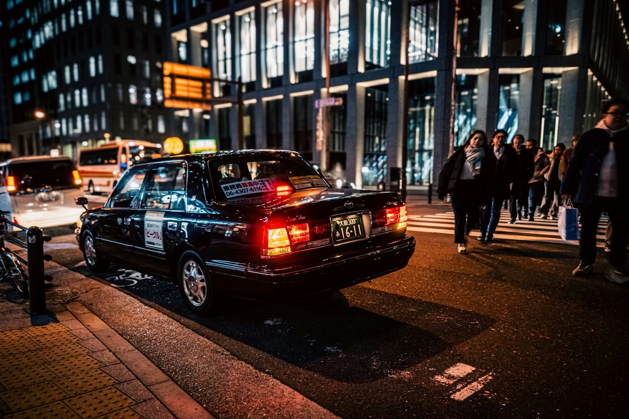 夜の街角で並ぶクラシックな黒いセダンと歩行者