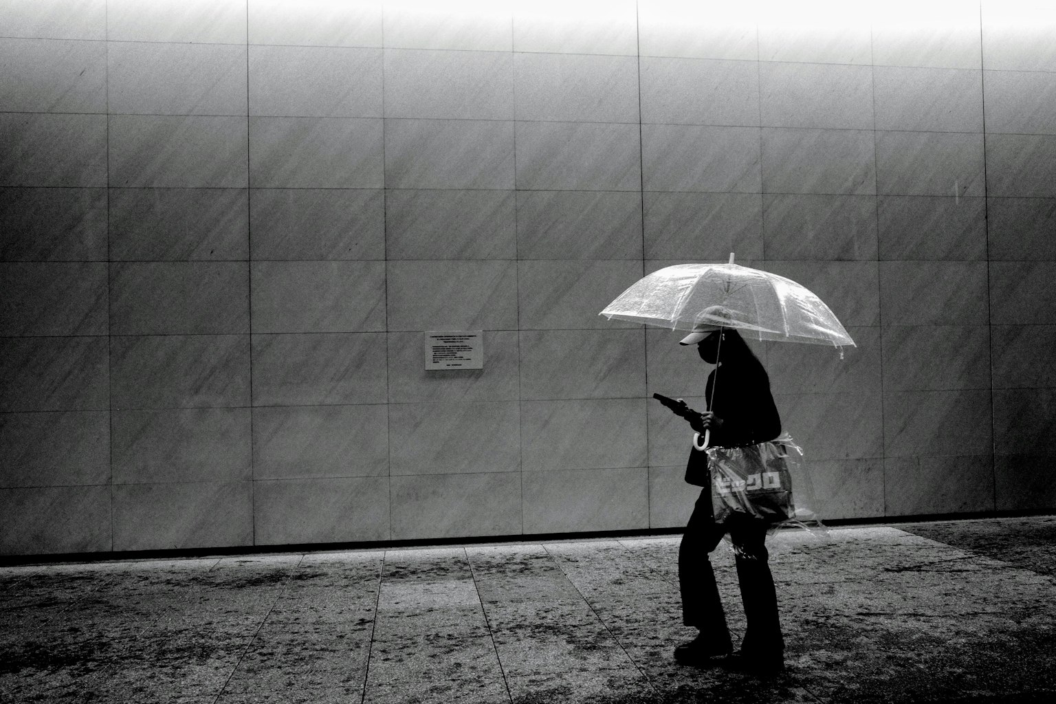 Person walking with a white umbrella in a monochrome image