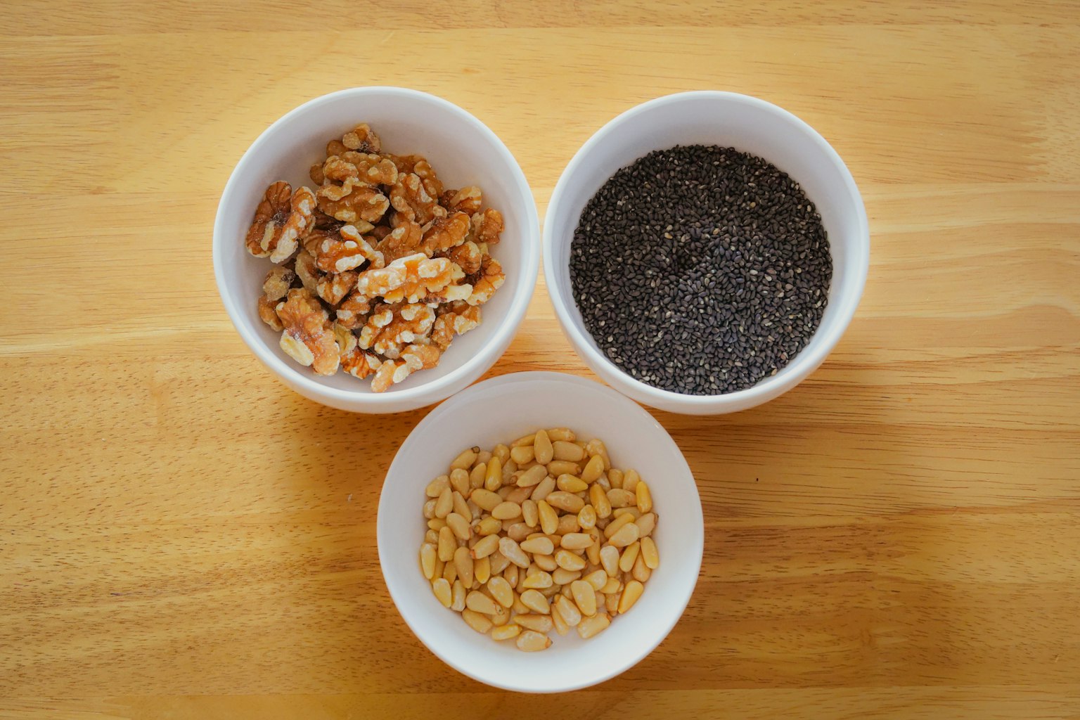 Collection of nuts and seeds in three white bowls
