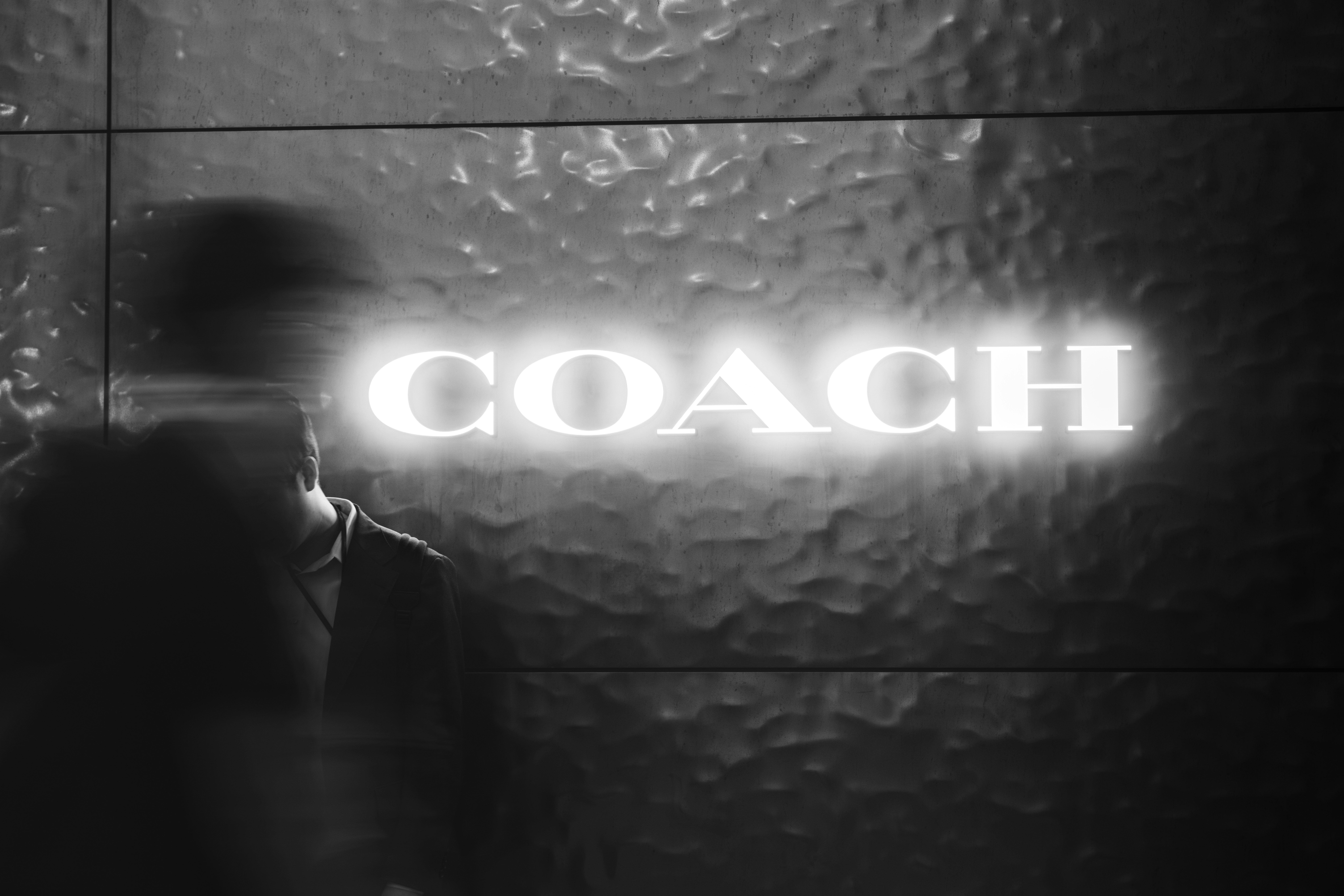 黒い背景に浮かぶCOACHのロゴ文字