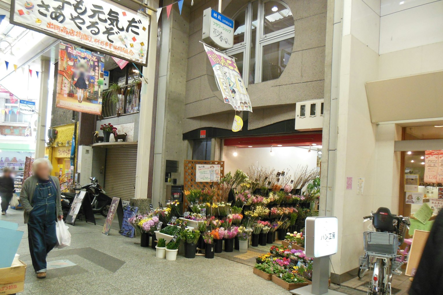 Scena vivace all'ingresso di un'arcata commerciale con un negozio di fiori