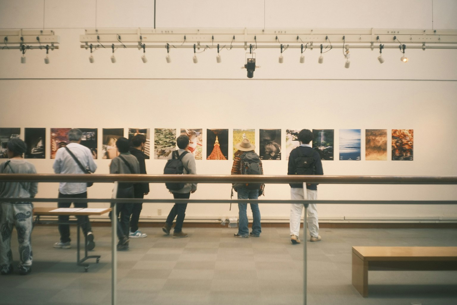Grupo de personas observando arte en una galería con carteles en la pared