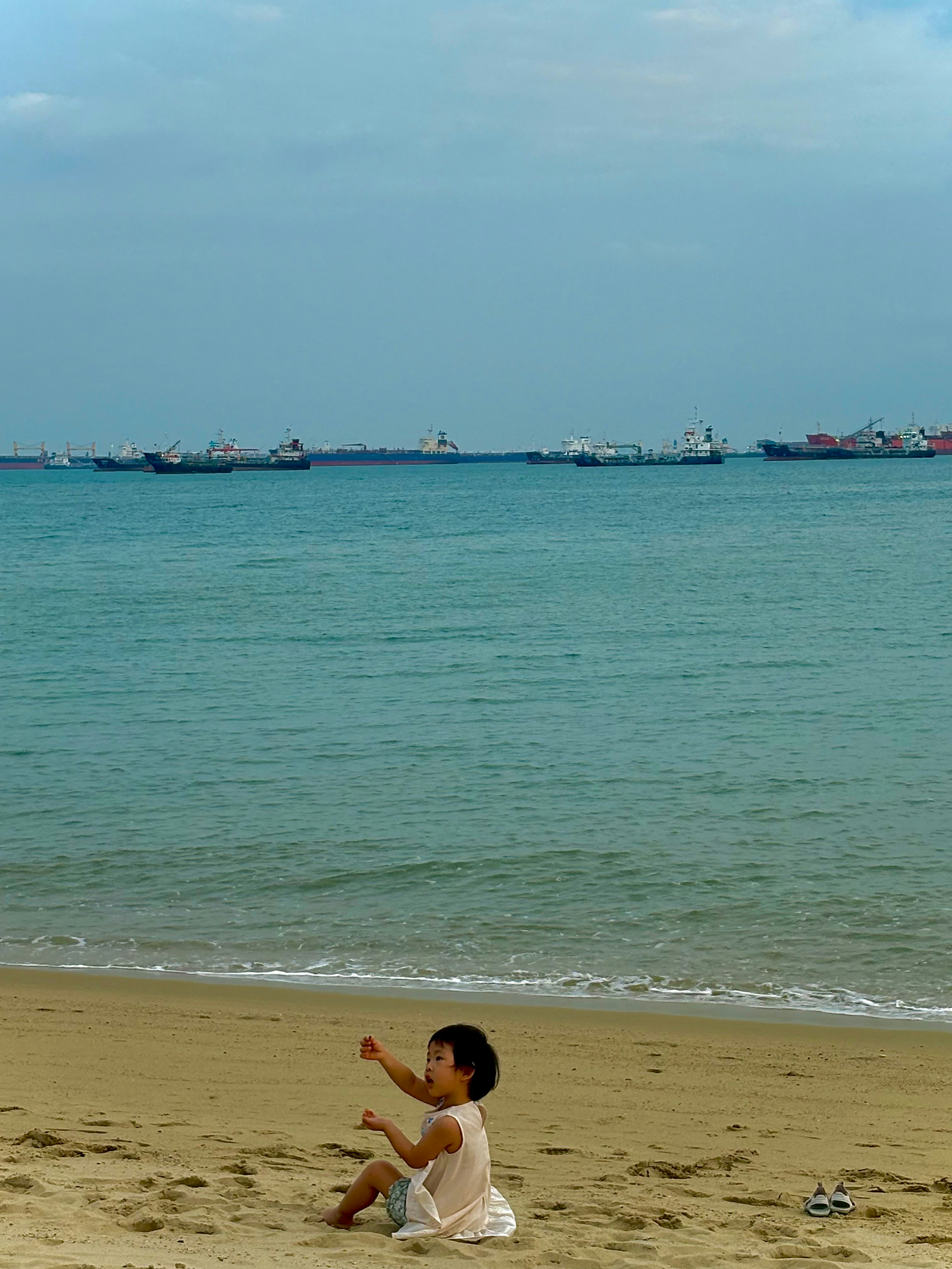 砂浜で遊ぶ子どもと穏やかな海の風景