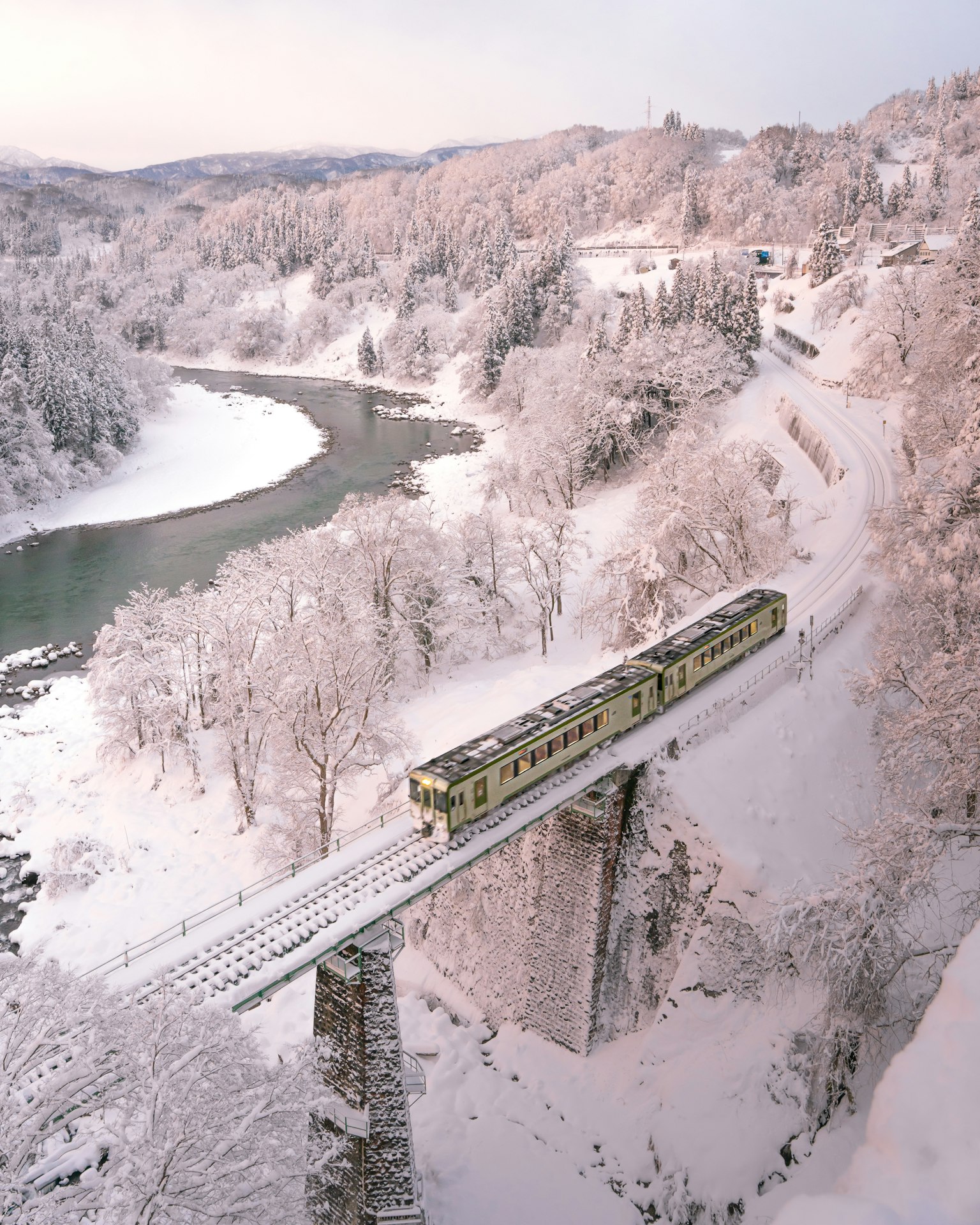 雪覆盖的桥上行驶的火车和河流的美丽景色