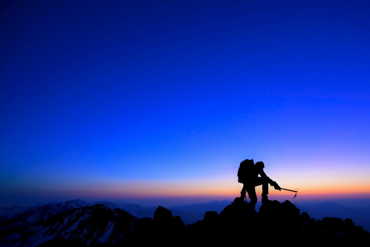 两名登山者在山顶上与黄昏的天空形成剪影